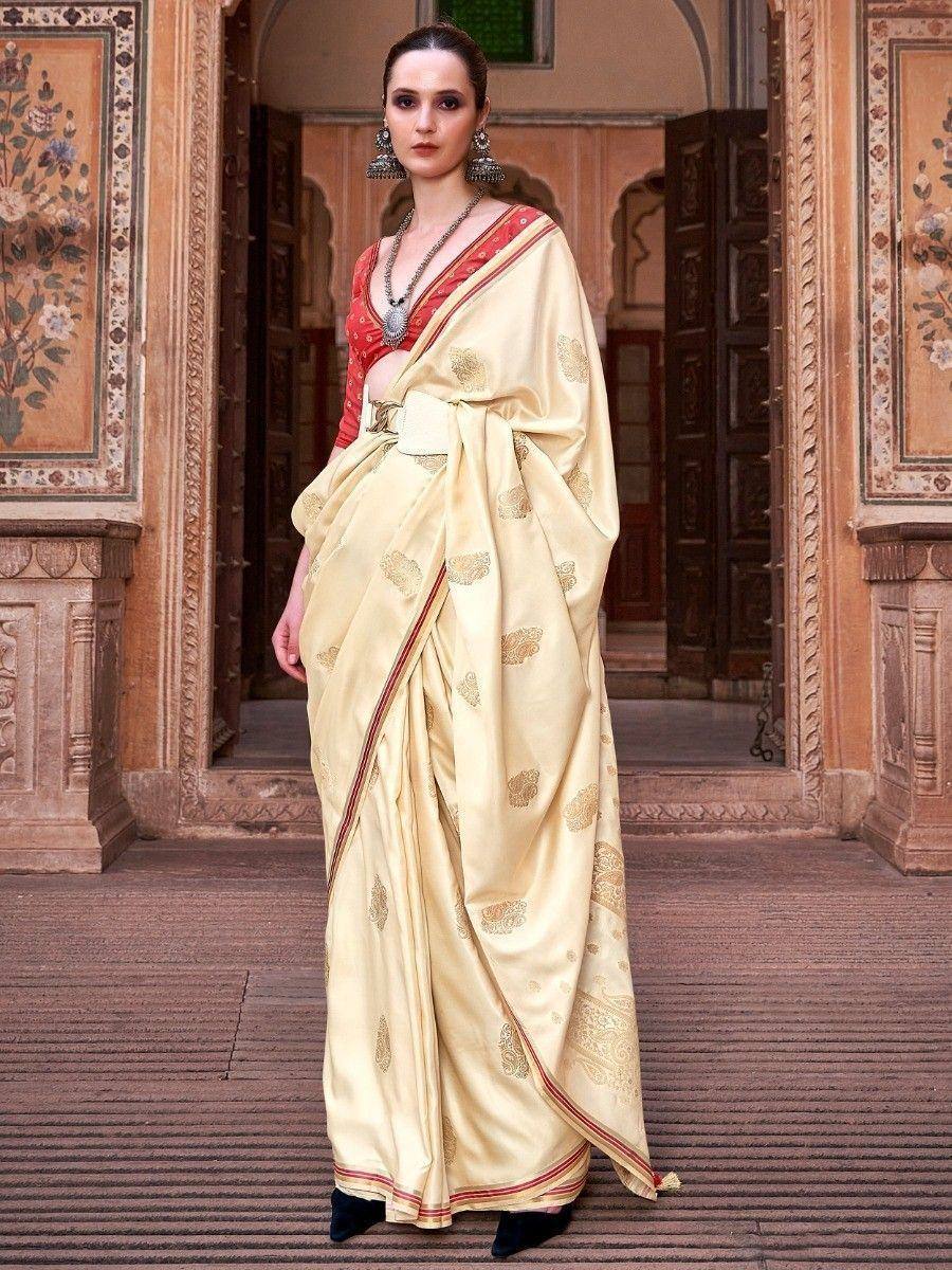 Elegant cream saree with gold motifs and red border, paired with red blouse, perfect for Indian ethnic occasions.