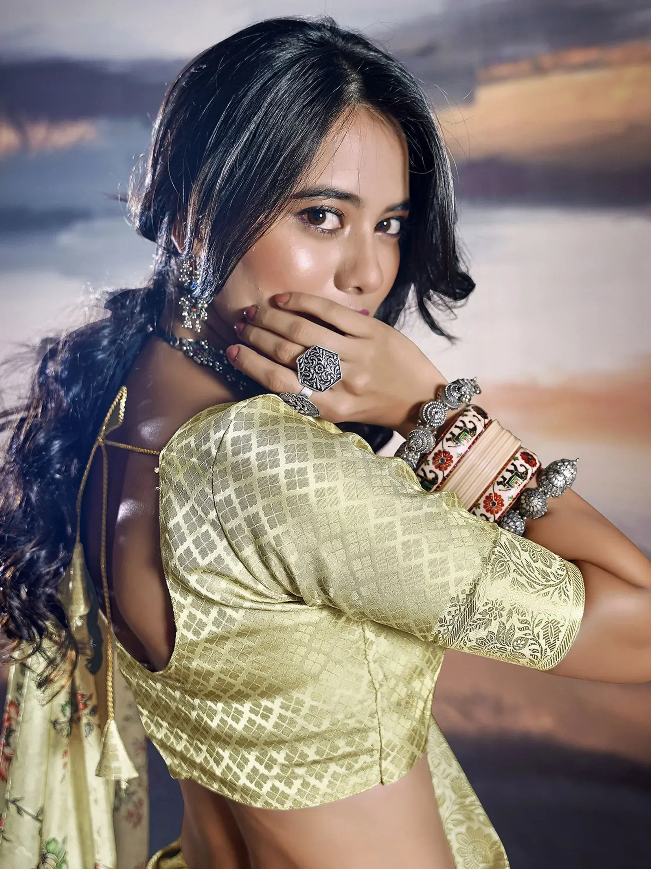 Woman in golden ethnic blouse with intricate jewelry and floral dupatta, showcasing Indian designer wear.