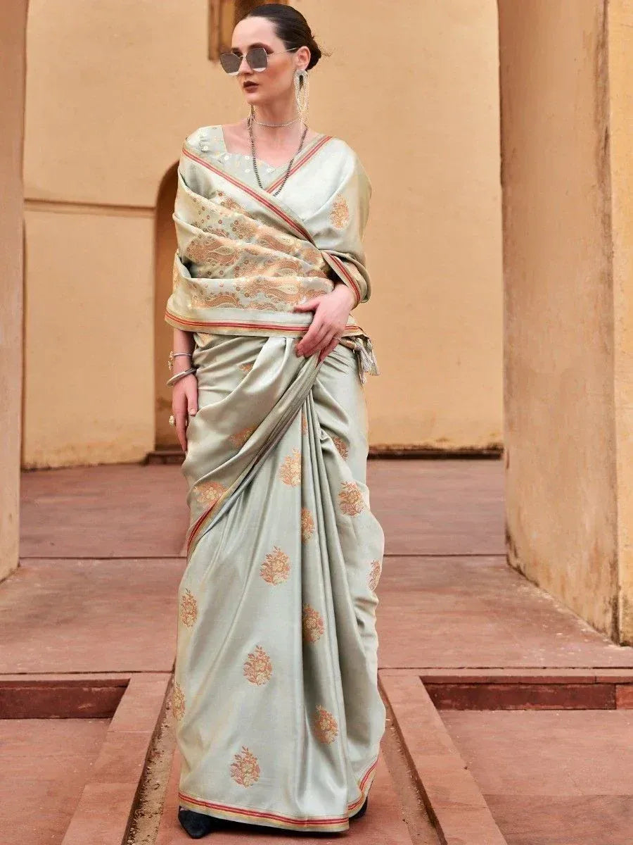 Elegant light green designer saree with gold floral motifs and red border, styled for Indian ethnic wear.