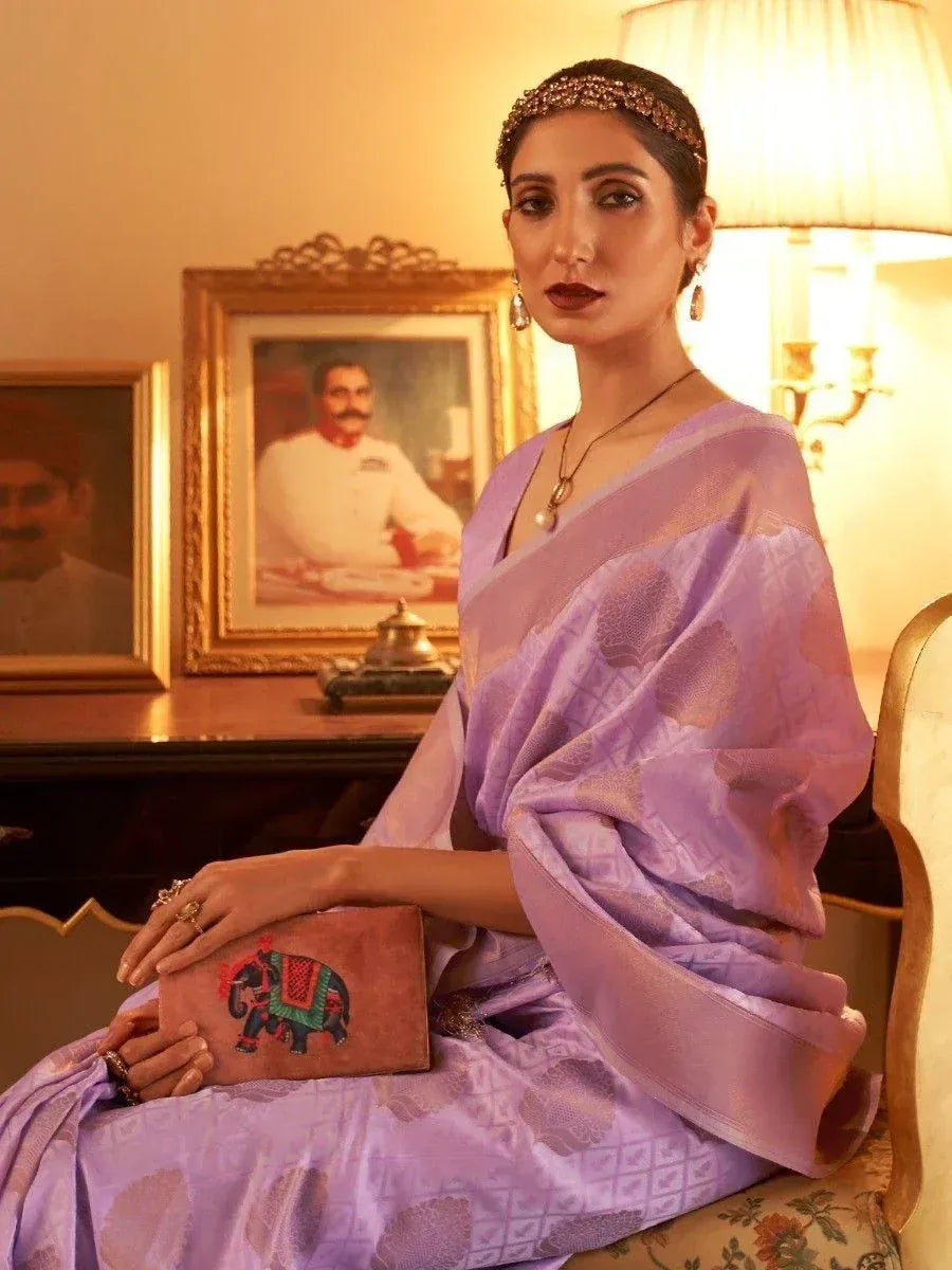 Woman in lavender designer saree with elephant clutch, ethnic jewelry, and traditional Indian decor
