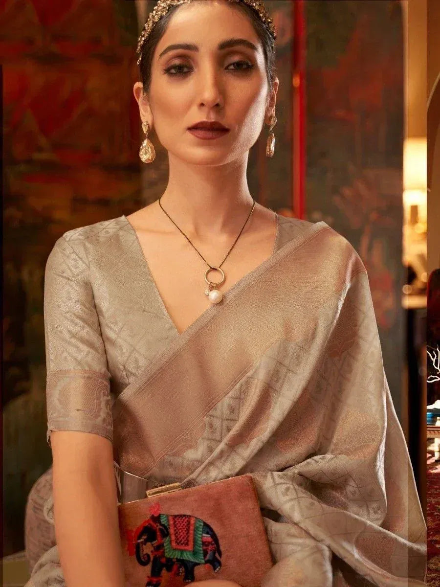 Elegant woman in designer saree with elephant embroidery, traditional jewelry, and ethnic clutch for Indian occasions.