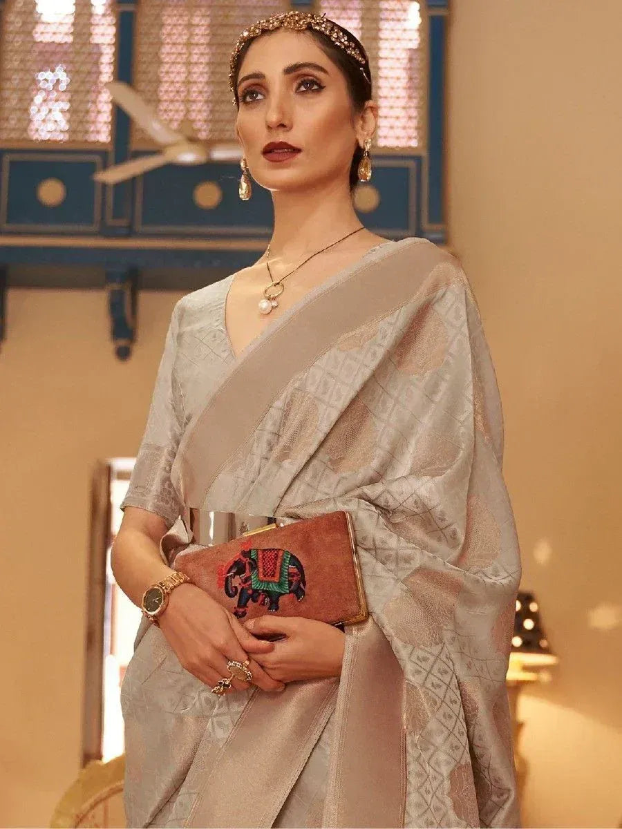 Elegant woman in light grey designer saree with elephant clutch, traditional jewelry, and headpiece for ethnic occasions