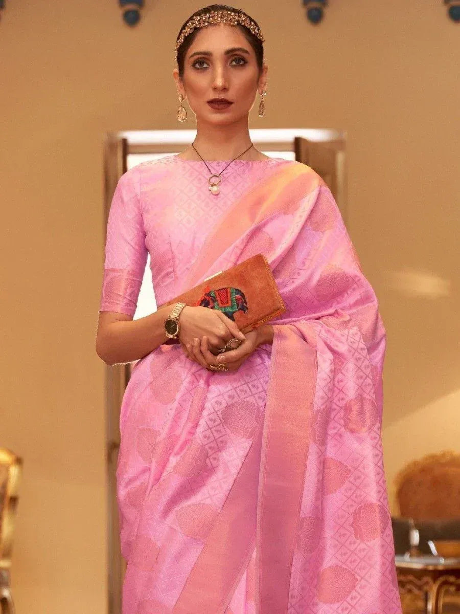 Pink designer saree with geometric print, paired with matching blouse and ethnic jewelry for festive occasions