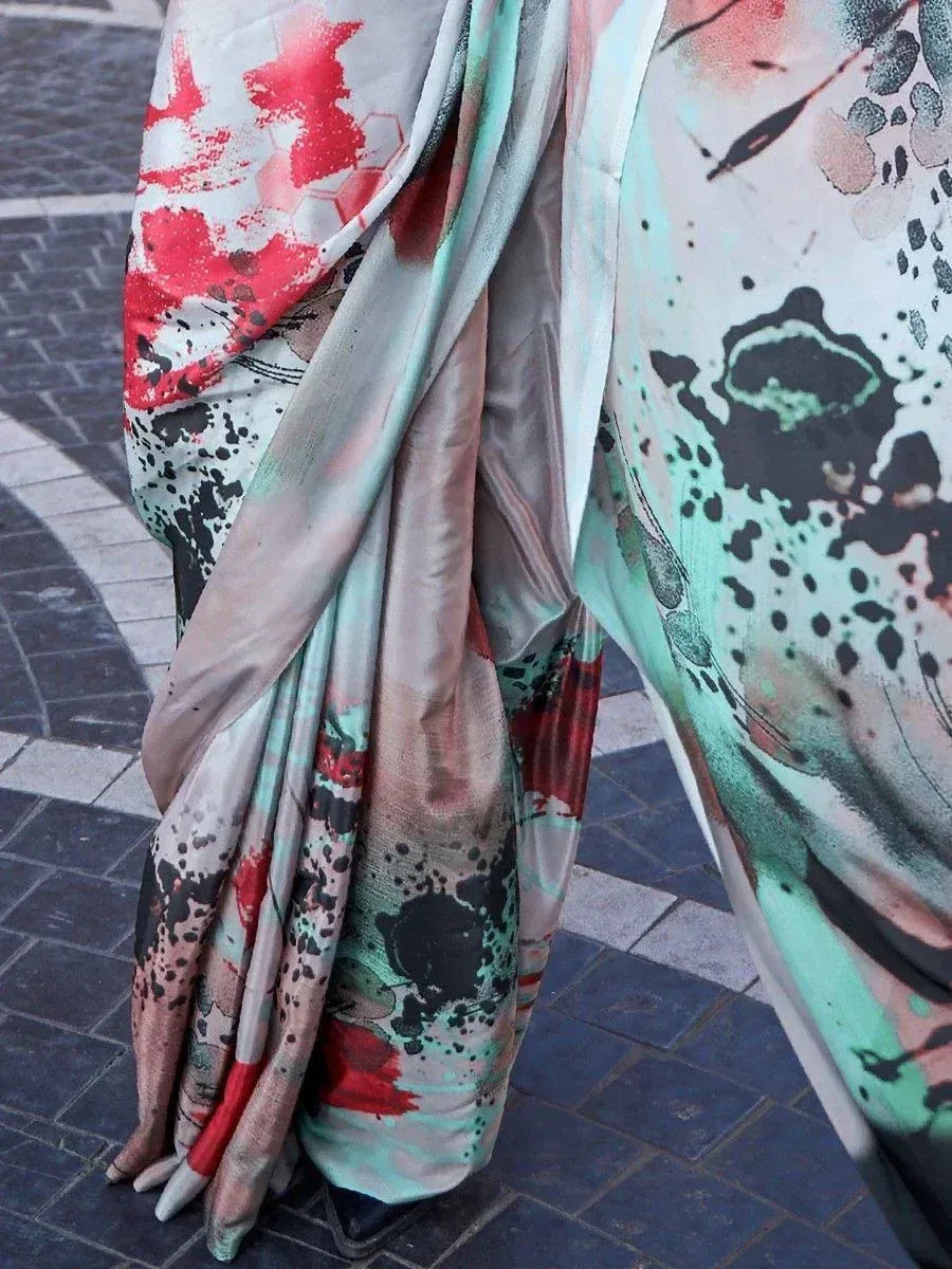 Abstract print saree with red, mint, and black splatter design, draped elegantly on pavement