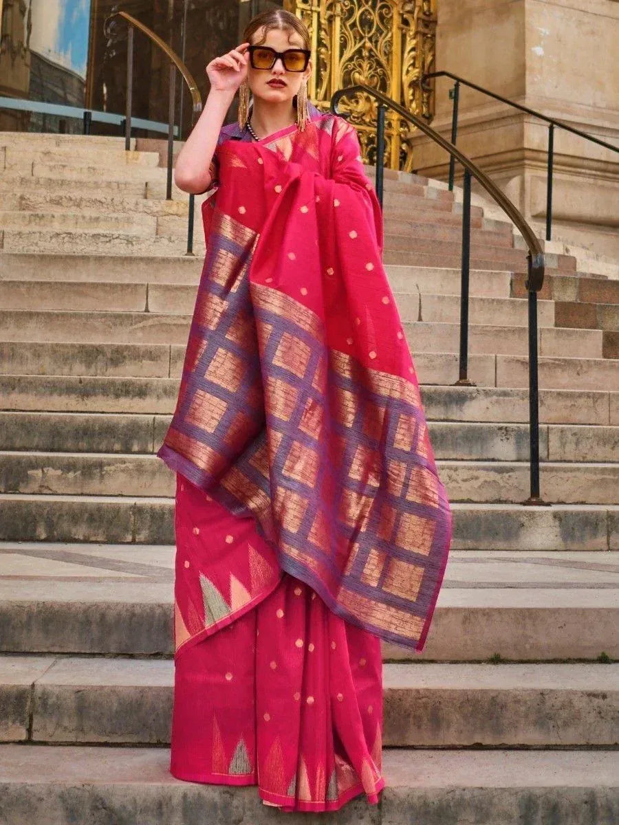 Woman in vibrant pink ethnic saree with gold and purple geometric border, styled for modern Indian fashion