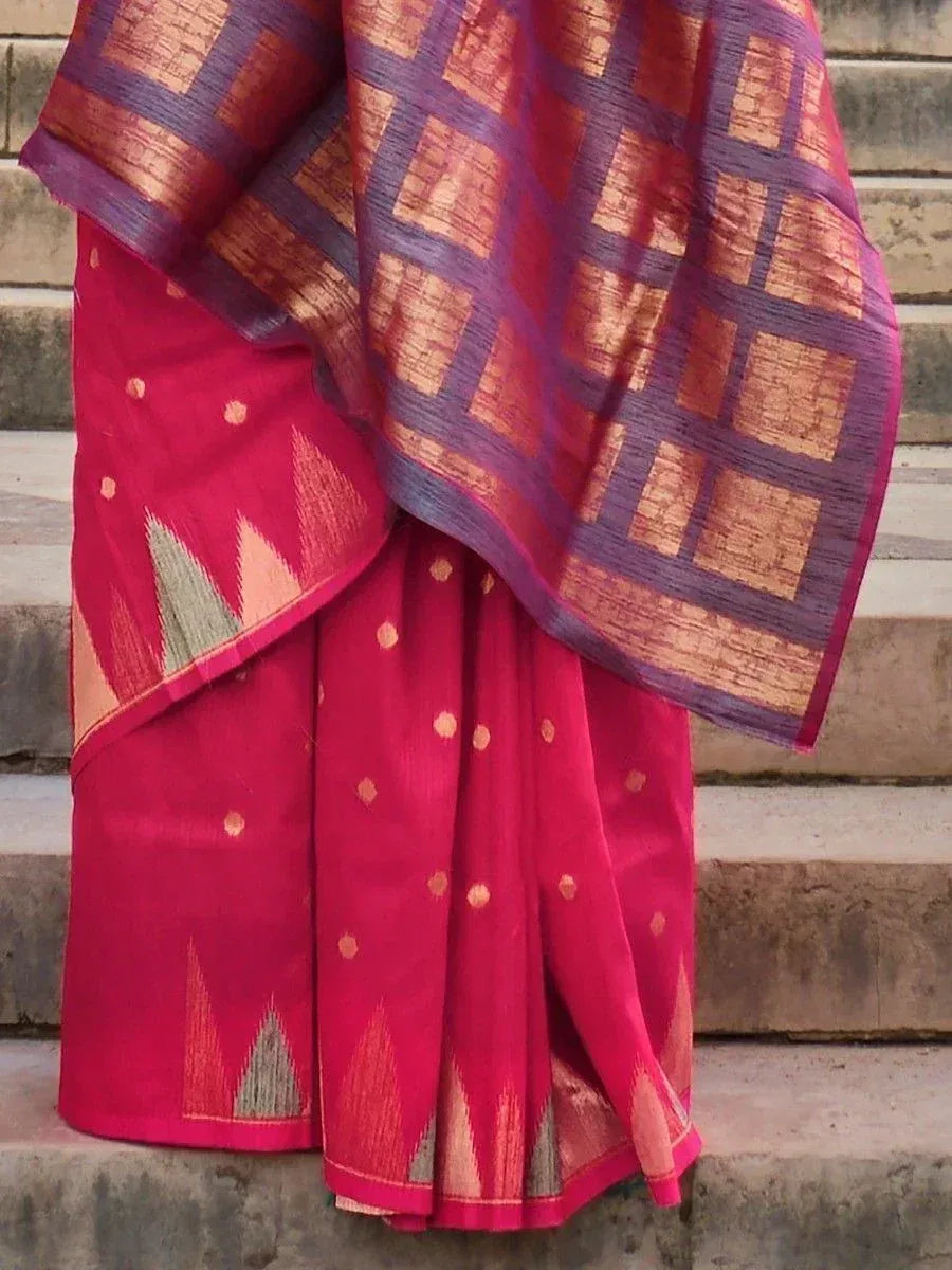 Vibrant pink saree with geometric ikat patterns and gold accents, draped elegantly on stone steps.