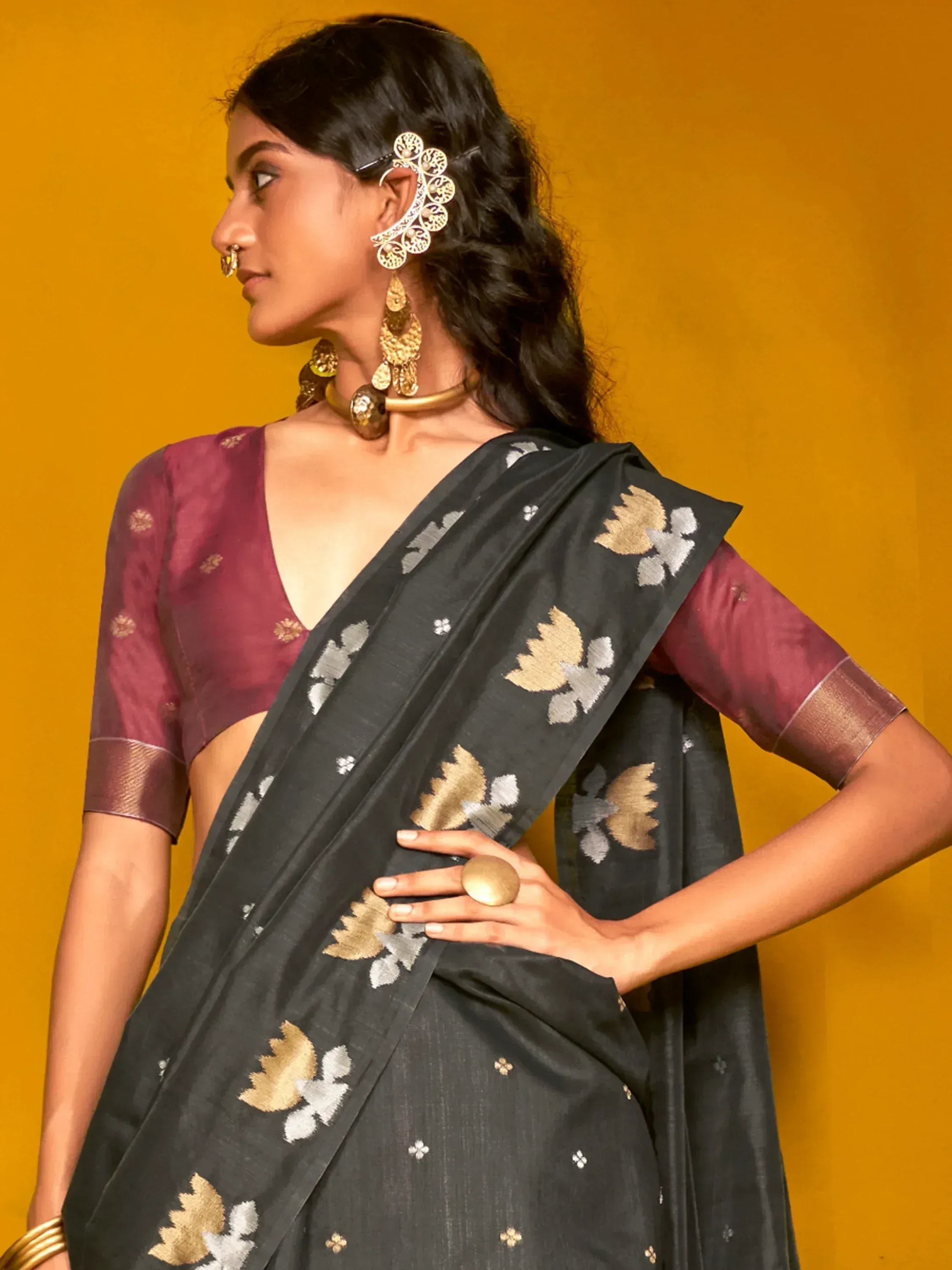 Black saree with gold and silver floral embroidery, paired with maroon blouse, styled with traditional Indian jewelry.