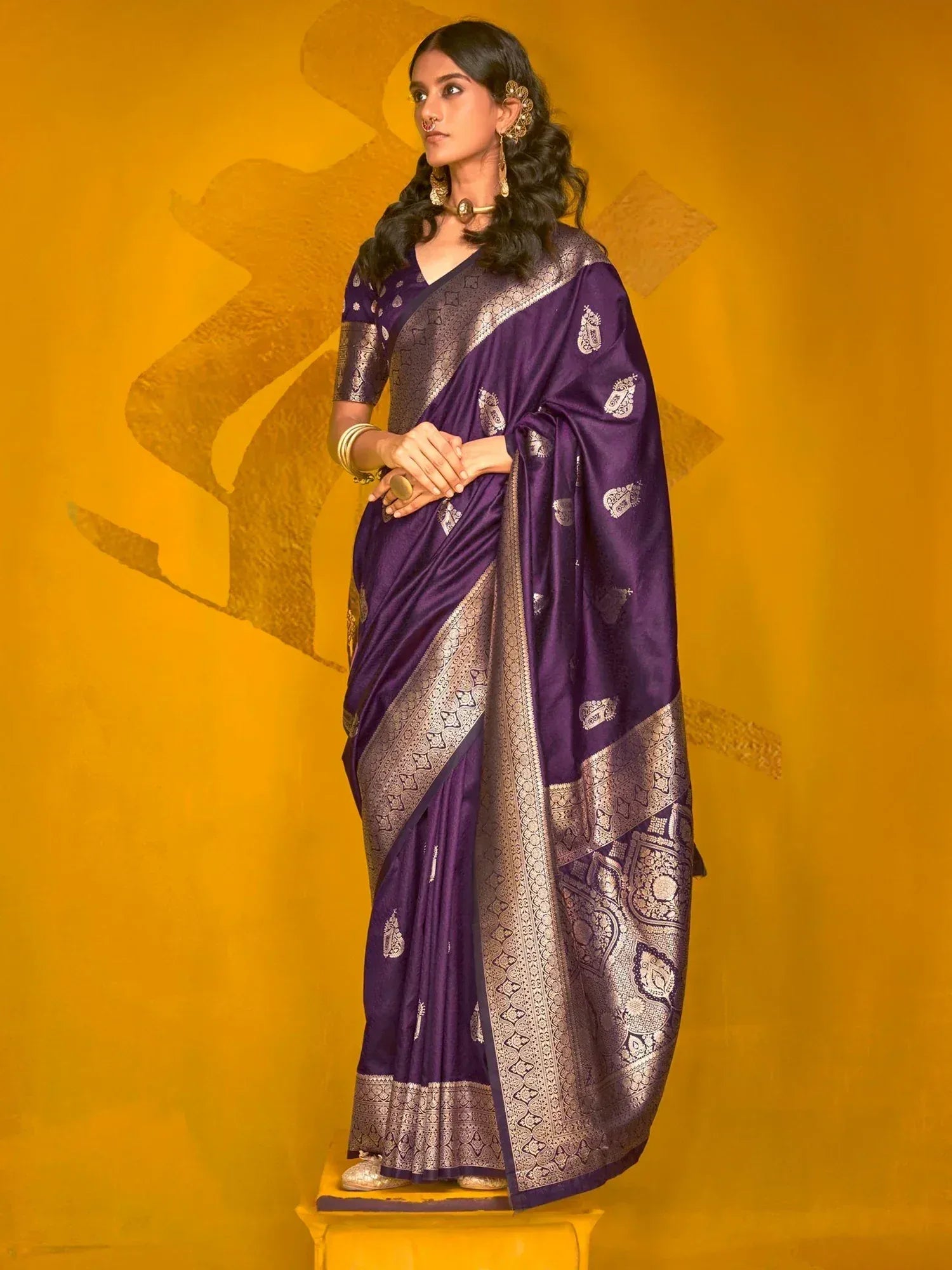 Purple silk saree with gold zari border and paisley motifs, styled with traditional jewelry for ethnic occasions