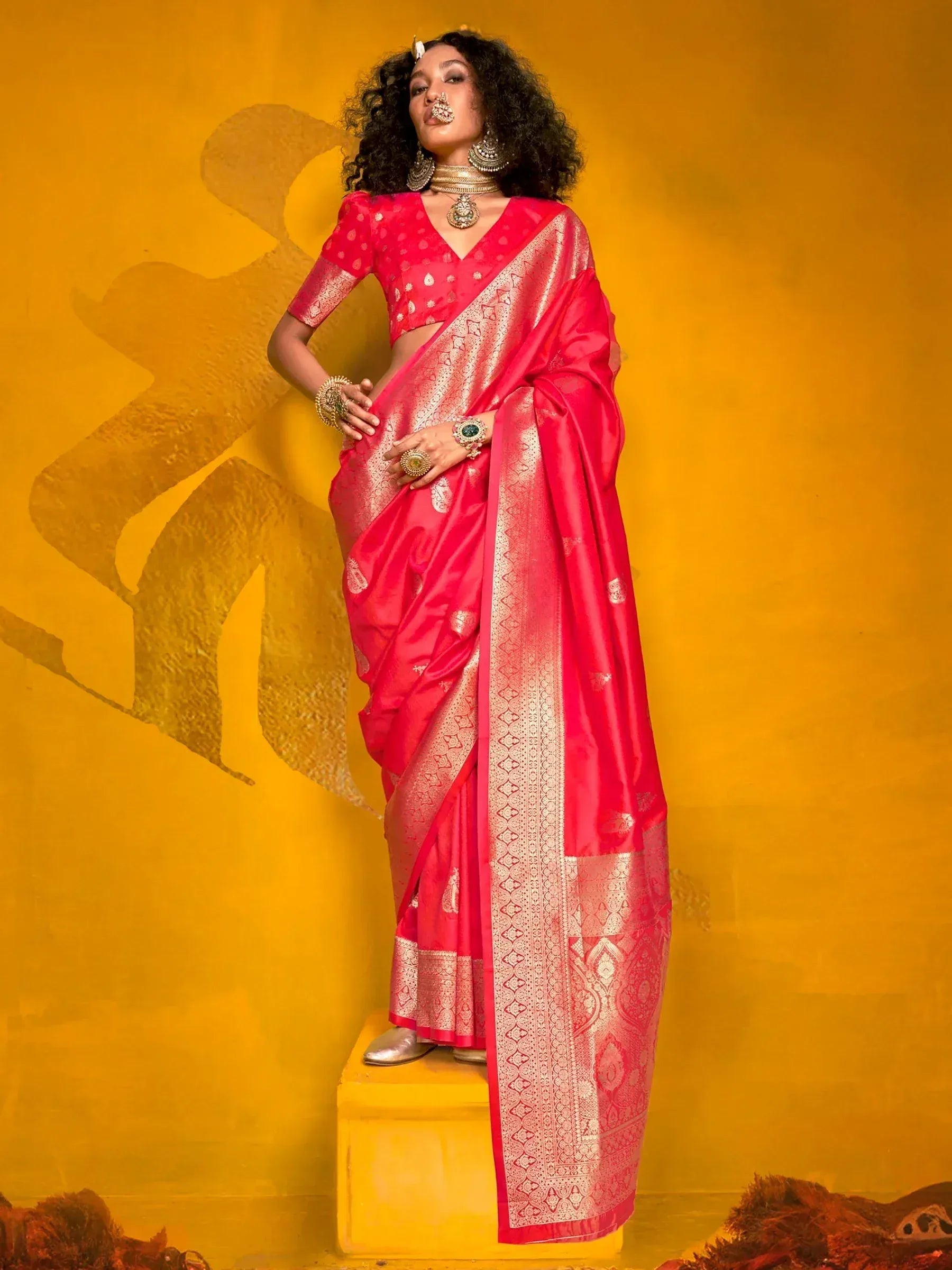 Vibrant pink silk saree with gold zari border and blouse, styled with traditional Indian jewelry against yellow backdrop