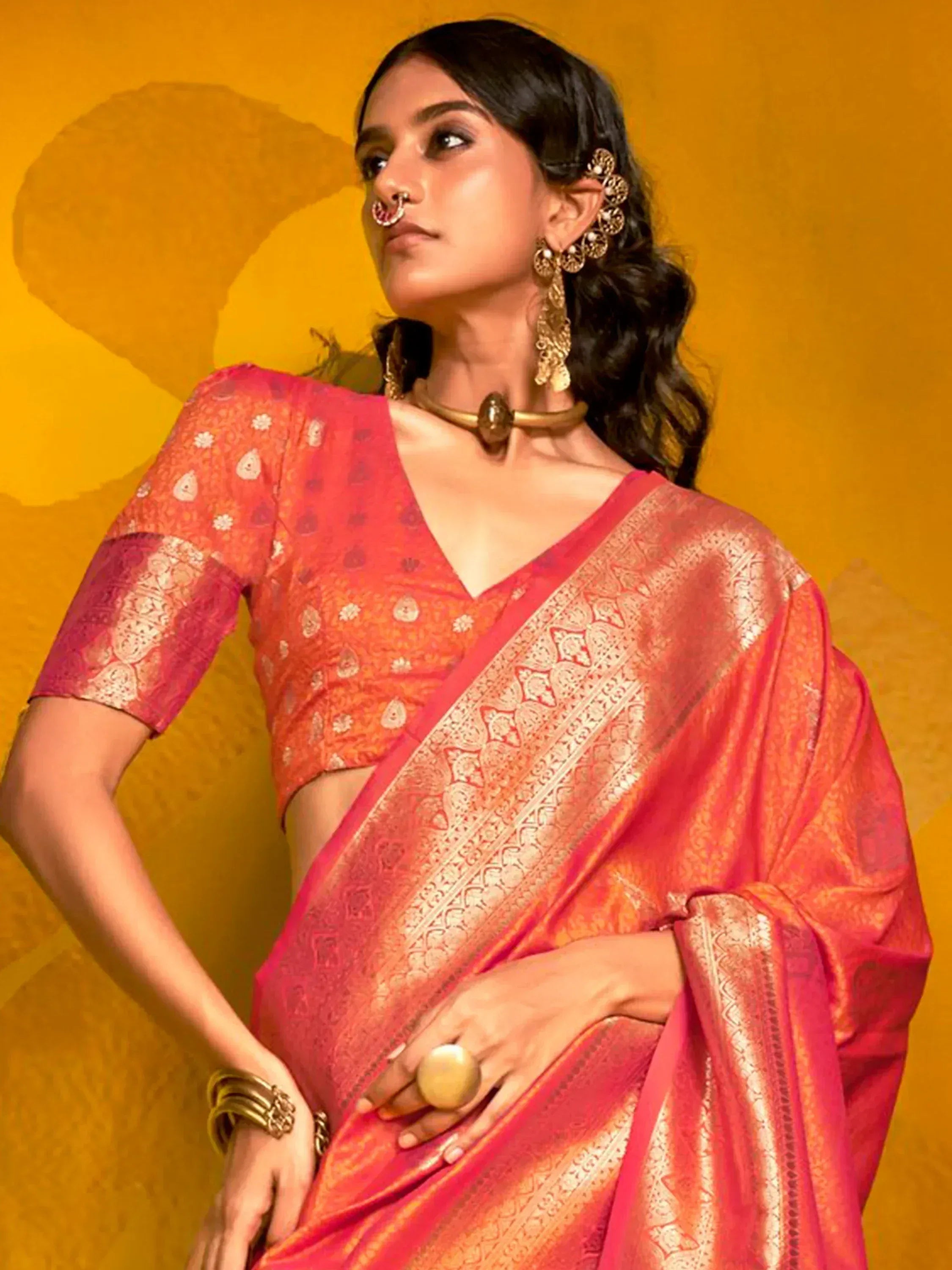 Woman in vibrant pink and orange designer saree with gold embroidery, traditional Indian ethnic wear