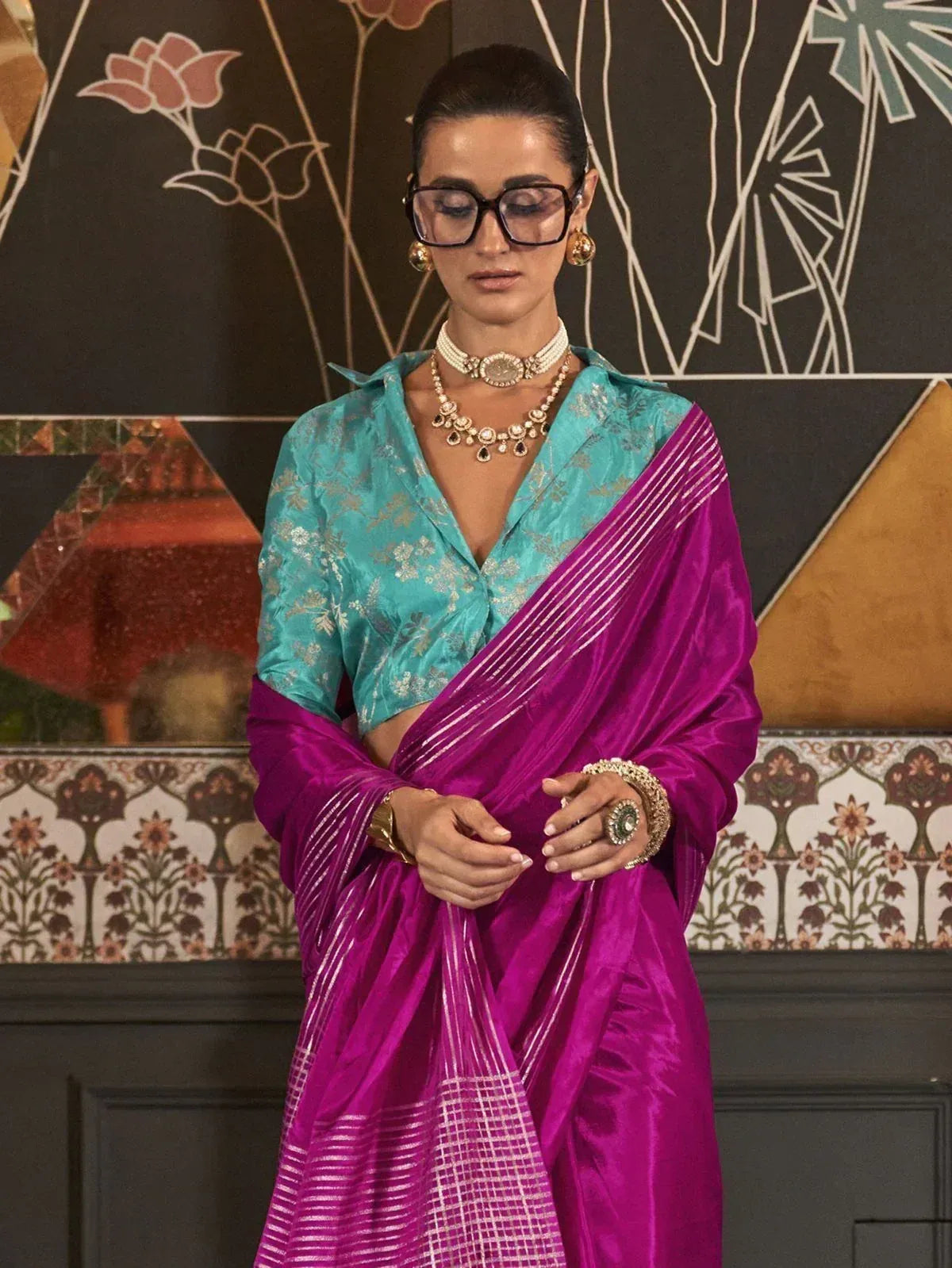 Vibrant purple saree with gold stripes paired with turquoise blouse, styled with traditional Indian jewelry