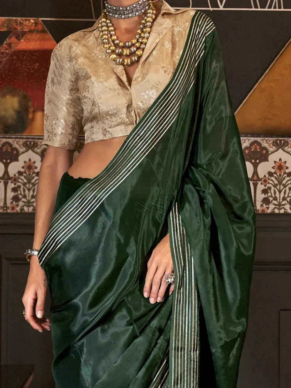 Emerald green silk saree with gold stripes, paired with a beige floral blouse and statement jewelry
