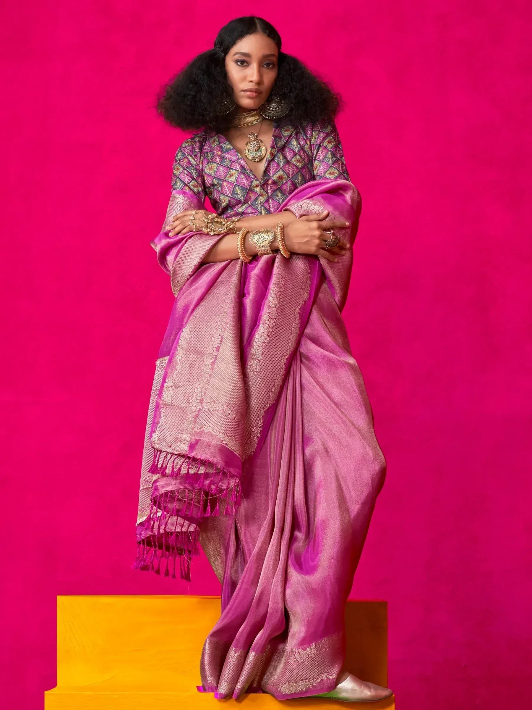 Woman in vibrant pink ethnic saree with gold embroidery, paired with designer blouse and traditional jewelry