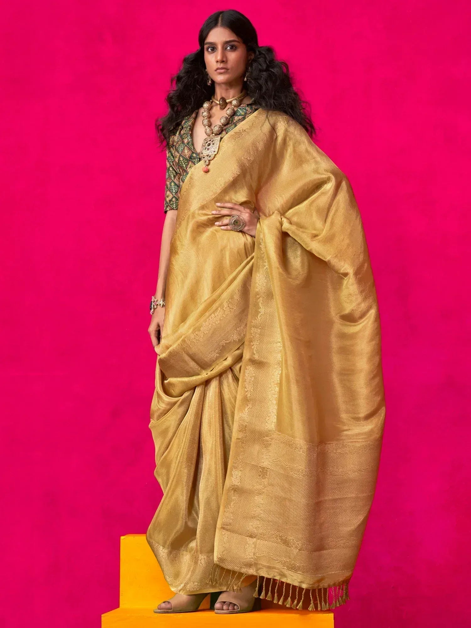Golden silk saree with intricate weave, paired with designer blouse and traditional jewelry