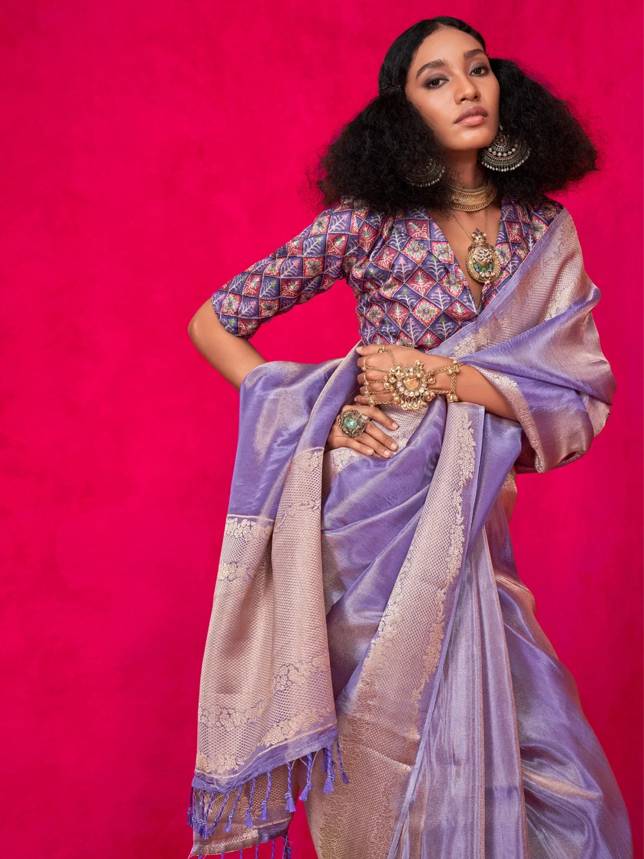 Purple designer saree with gold embroidery and tassels, paired with a patterned blouse and traditional jewelry