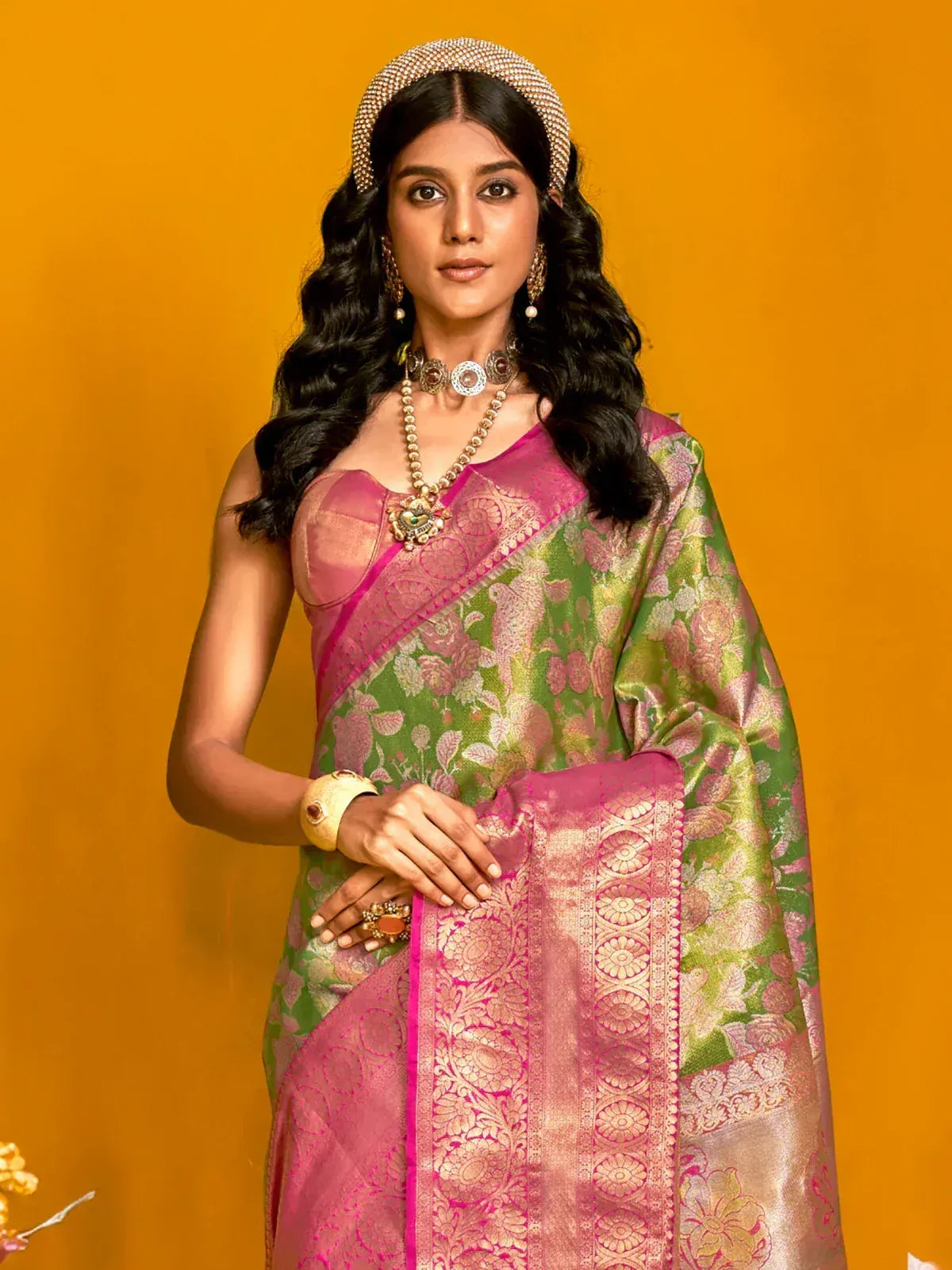 Green and pink floral saree with intricate gold embroidery and traditional jewelry
