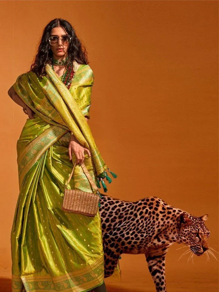 Woman in vibrant green silk saree with gold border, styled with sunglasses and woven bag, beside leopard
