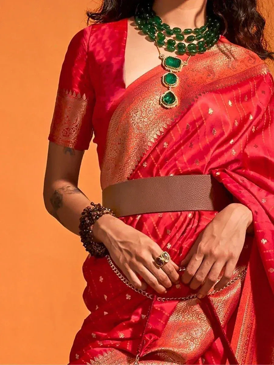 Red silk saree with gold embroidery, emerald jewelry, and brown belt for ethnic wear