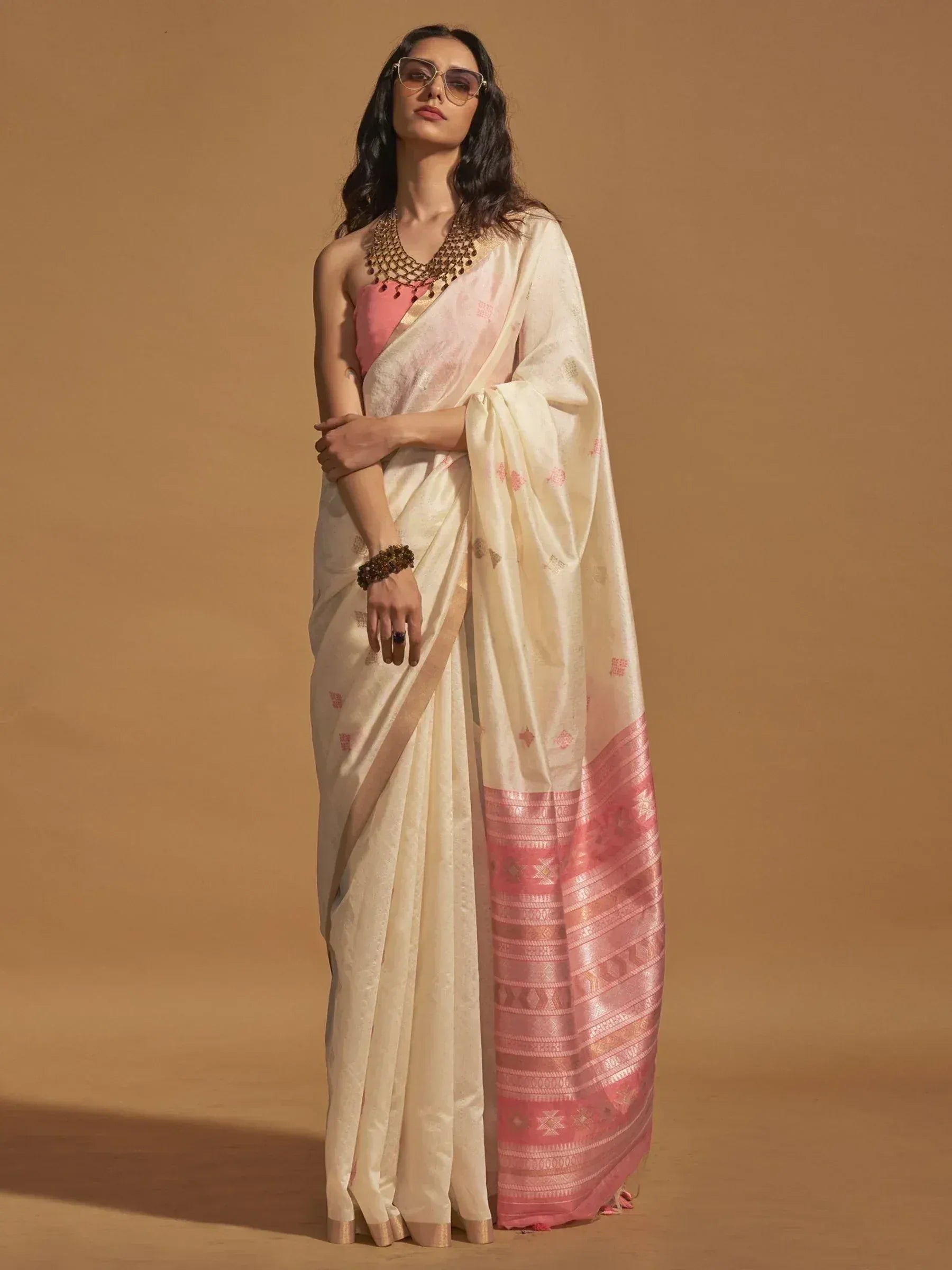 Cream and pink ethnic saree with woven border, paired with pink blouse and statement jewelry