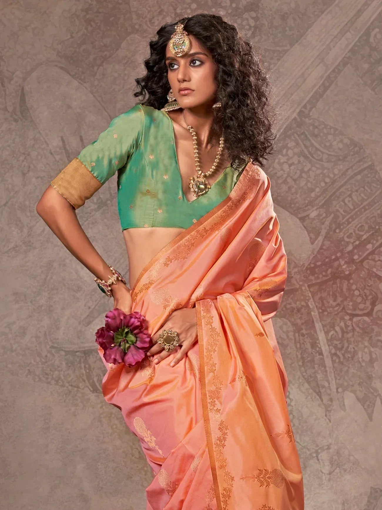 Woman in peach saree with green blouse, gold embroidery, and traditional jewelry for ethnic wear