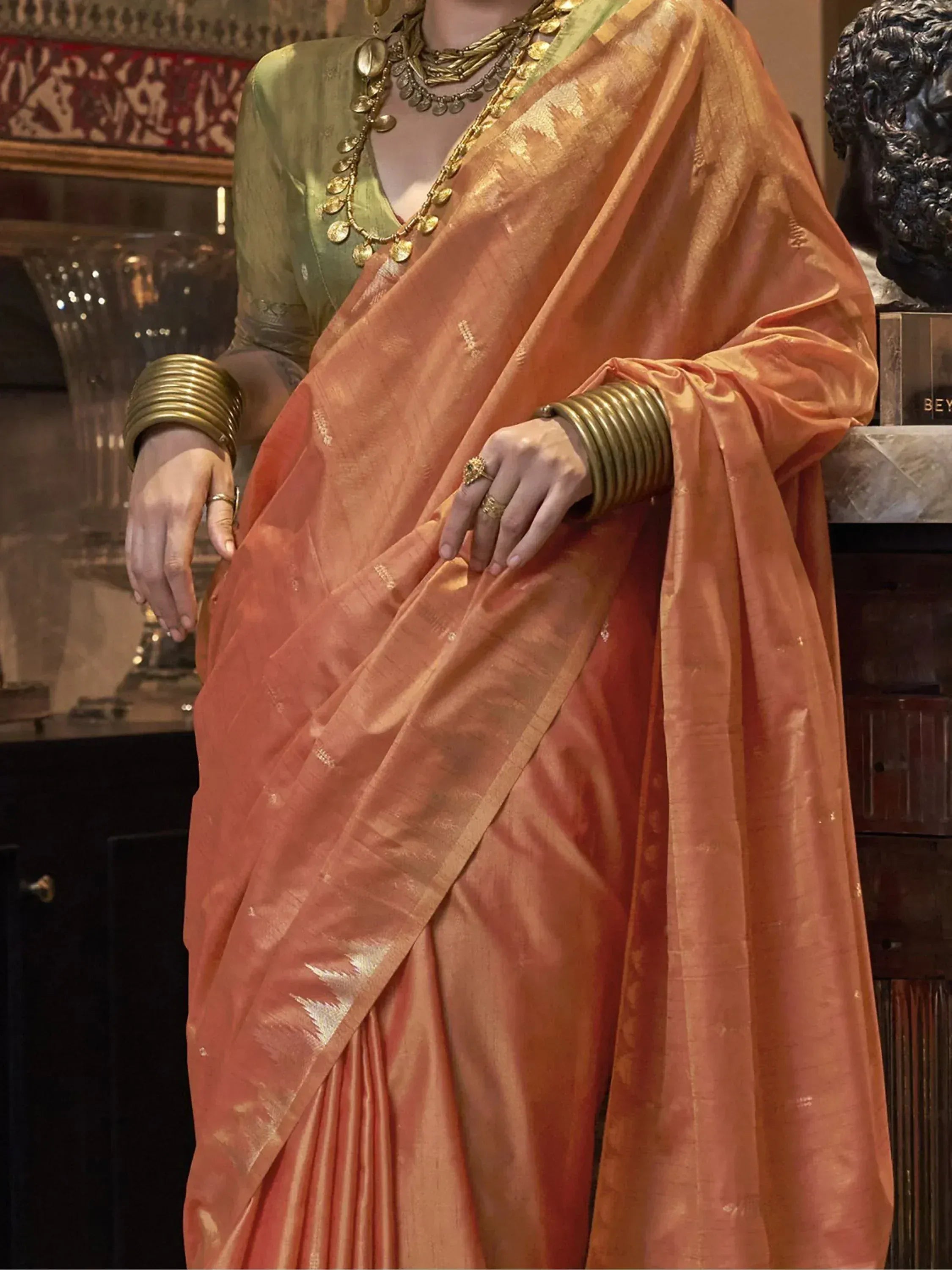 Elegant peach silk saree with gold zari, paired with green blouse and traditional jewelry for Indian ethnic wear