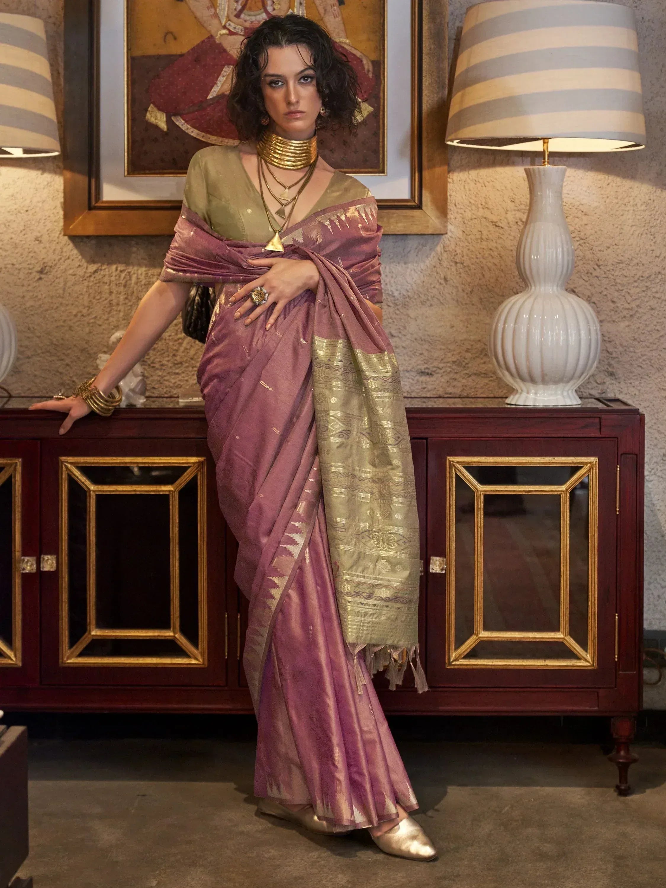 Woman in elegant purple and gold designer saree with traditional jewelry, perfect for Indian ethnic wear occasions.
