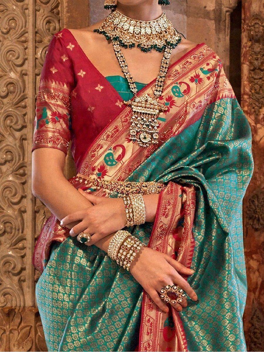 Teal and red designer saree with peacock motifs, paired with heavy gold jewelry for Indian ethnic wear