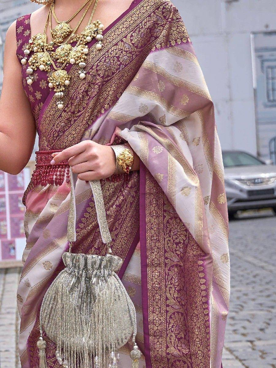 Purple and gold embroidered saree with heavy jewelry and tassel bag, perfect for Indian ethnic occasions