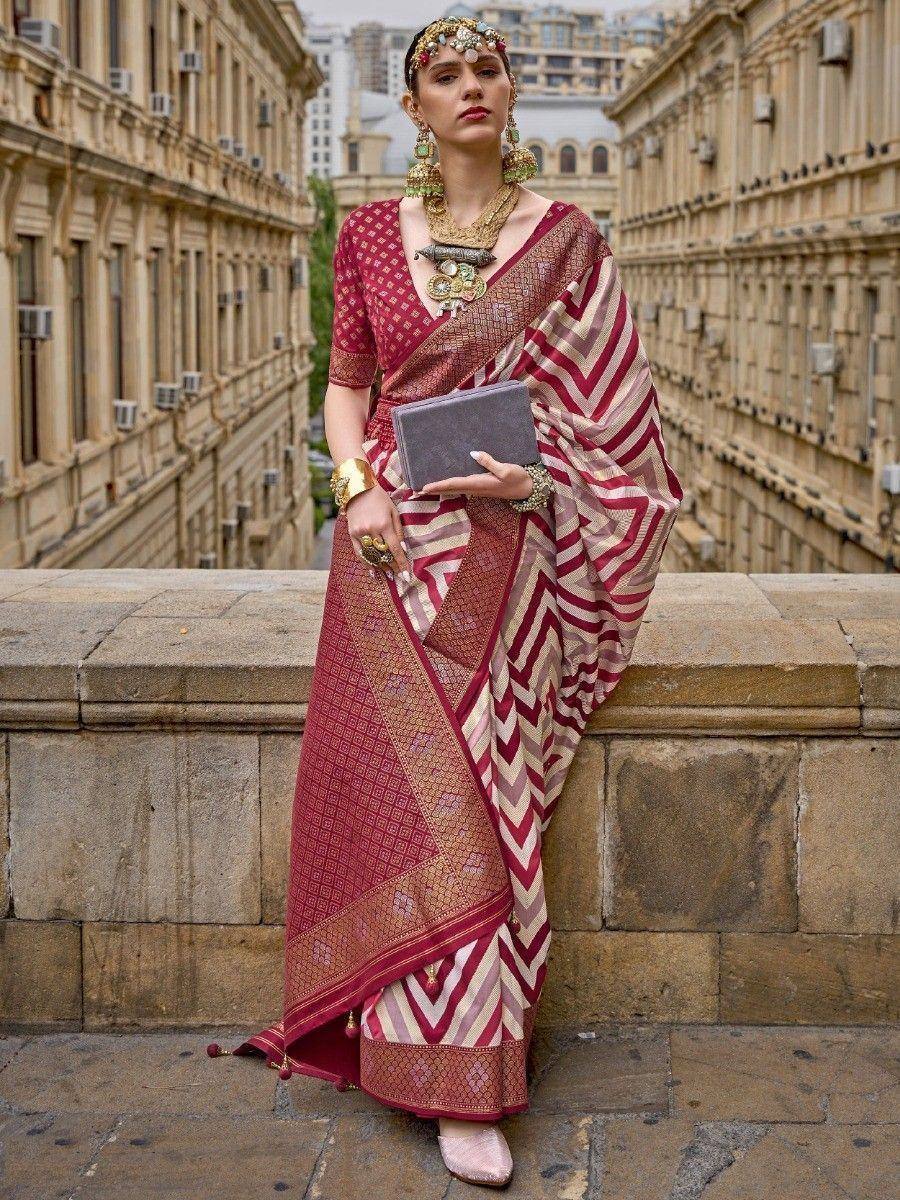 Woman in maroon and beige ethnic saree with chevron pattern, traditional jewelry, urban backdrop