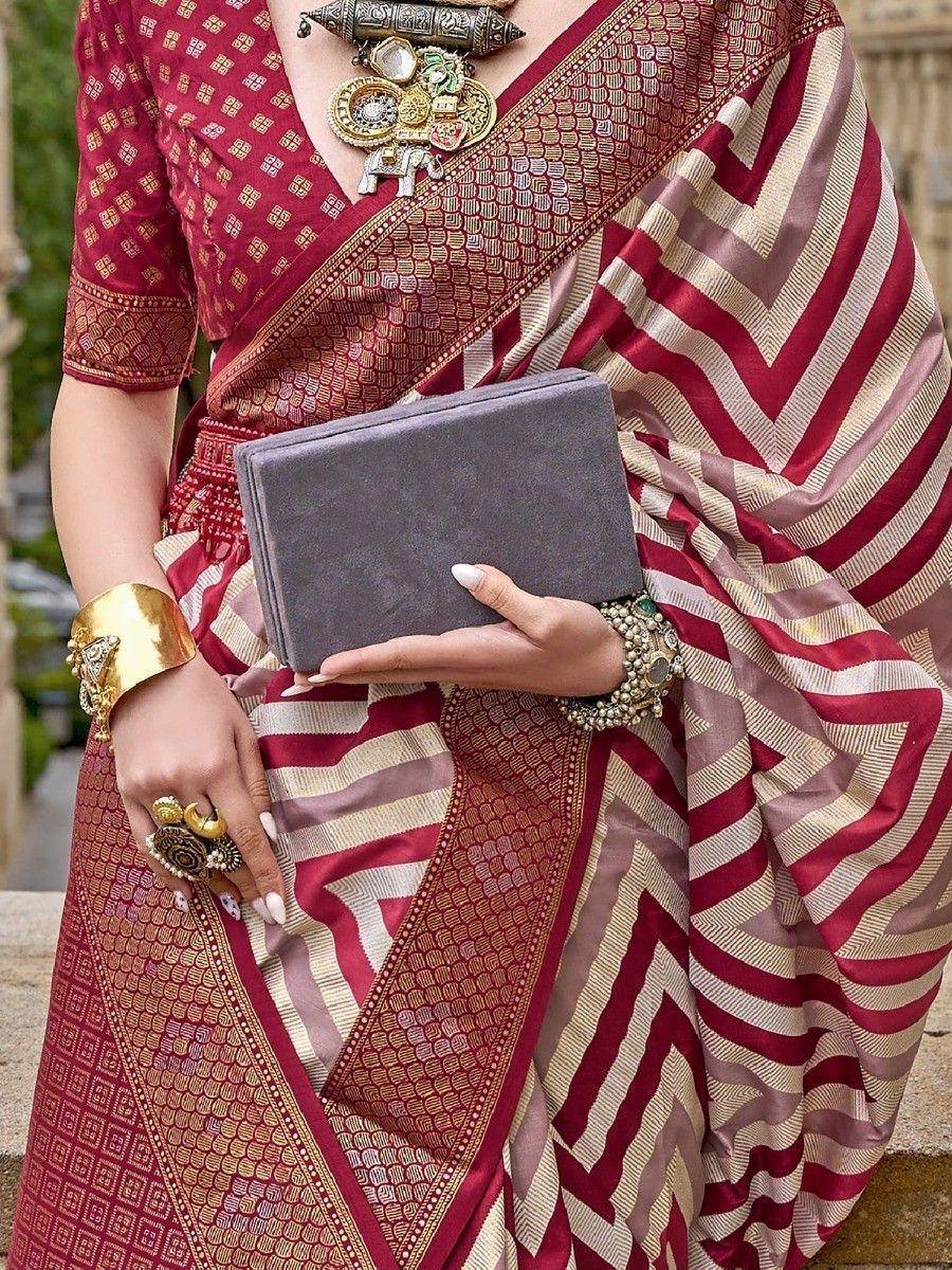 Maroon and gold ethnic saree with geometric patterns, paired with statement jewelry and a grey clutch
