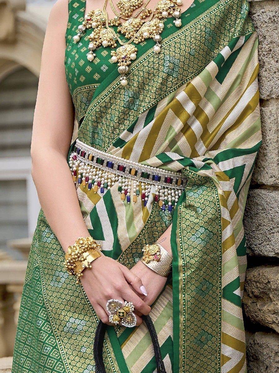 Green and gold designer saree with intricate patterns, embellished belt, and traditional Indian jewelry