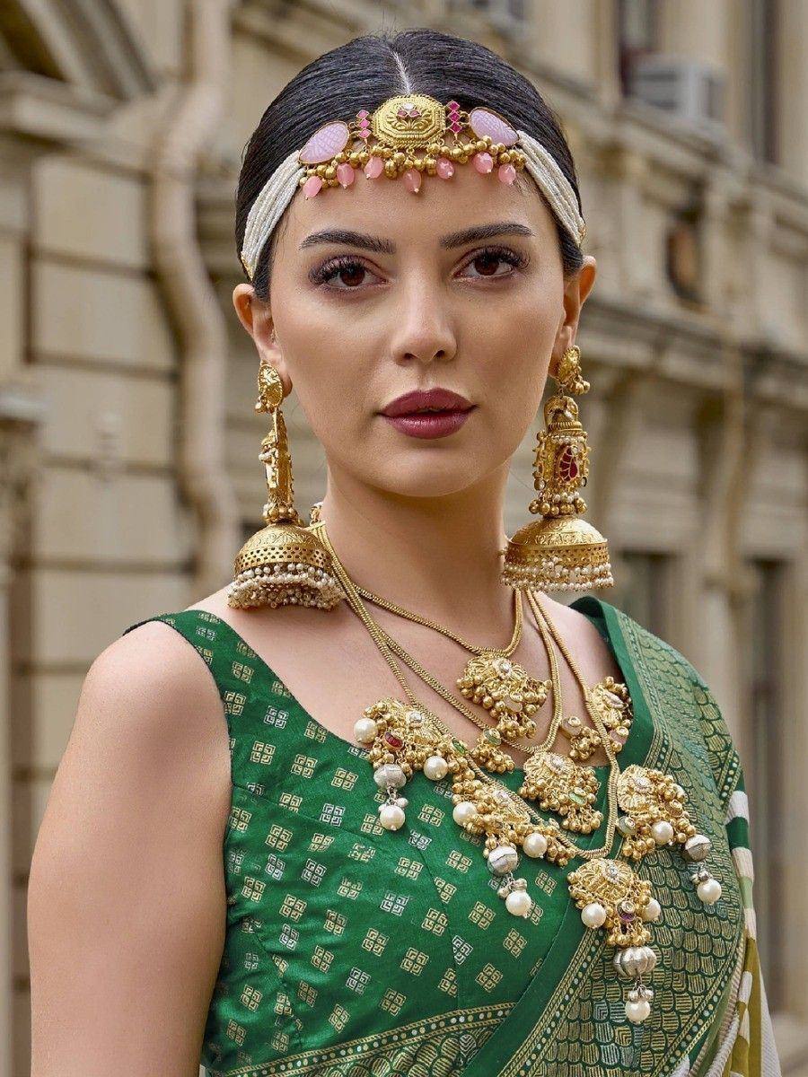 Woman in green ethnic saree with gold jewelry and maang tikka, perfect for Indian weddings and festivals