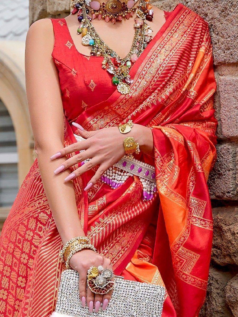 Red and gold ethnic saree with intricate patterns, paired with statement jewelry and a crystal clutch.