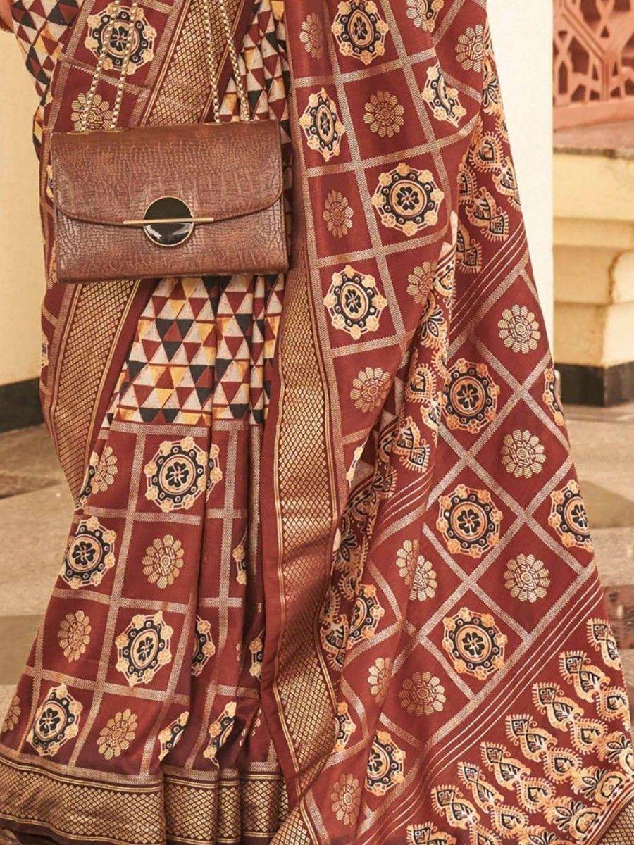 Maroon printed saree with gold floral motifs, paired with brown clutch, ethnic Indian wear