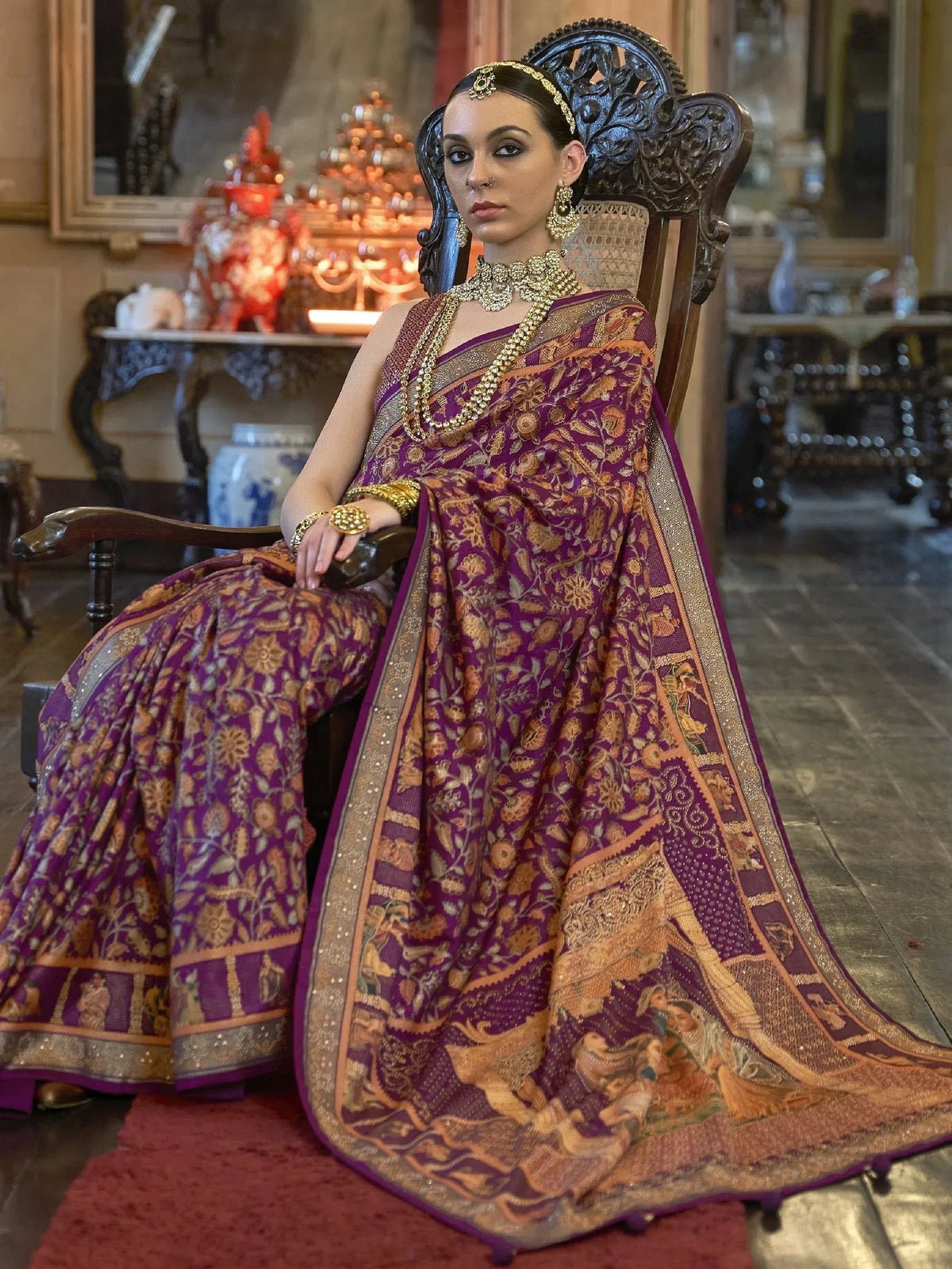 Woman in purple and gold designer saree with intricate floral and figurative motifs, traditional Indian ethnic wear