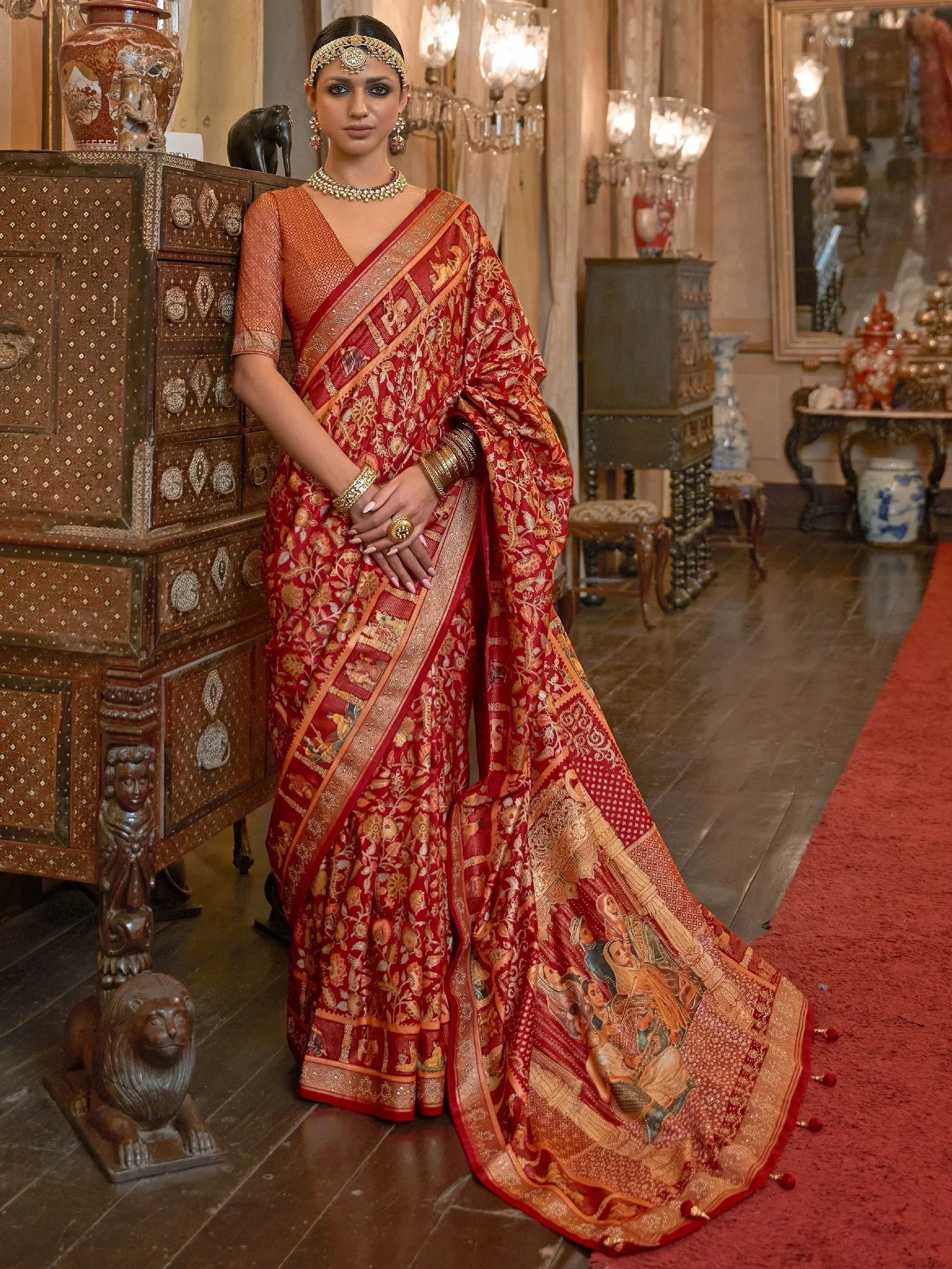 Red and gold designer saree with intricate embroidery and traditional Indian motifs, perfect for weddings and festive occasions.