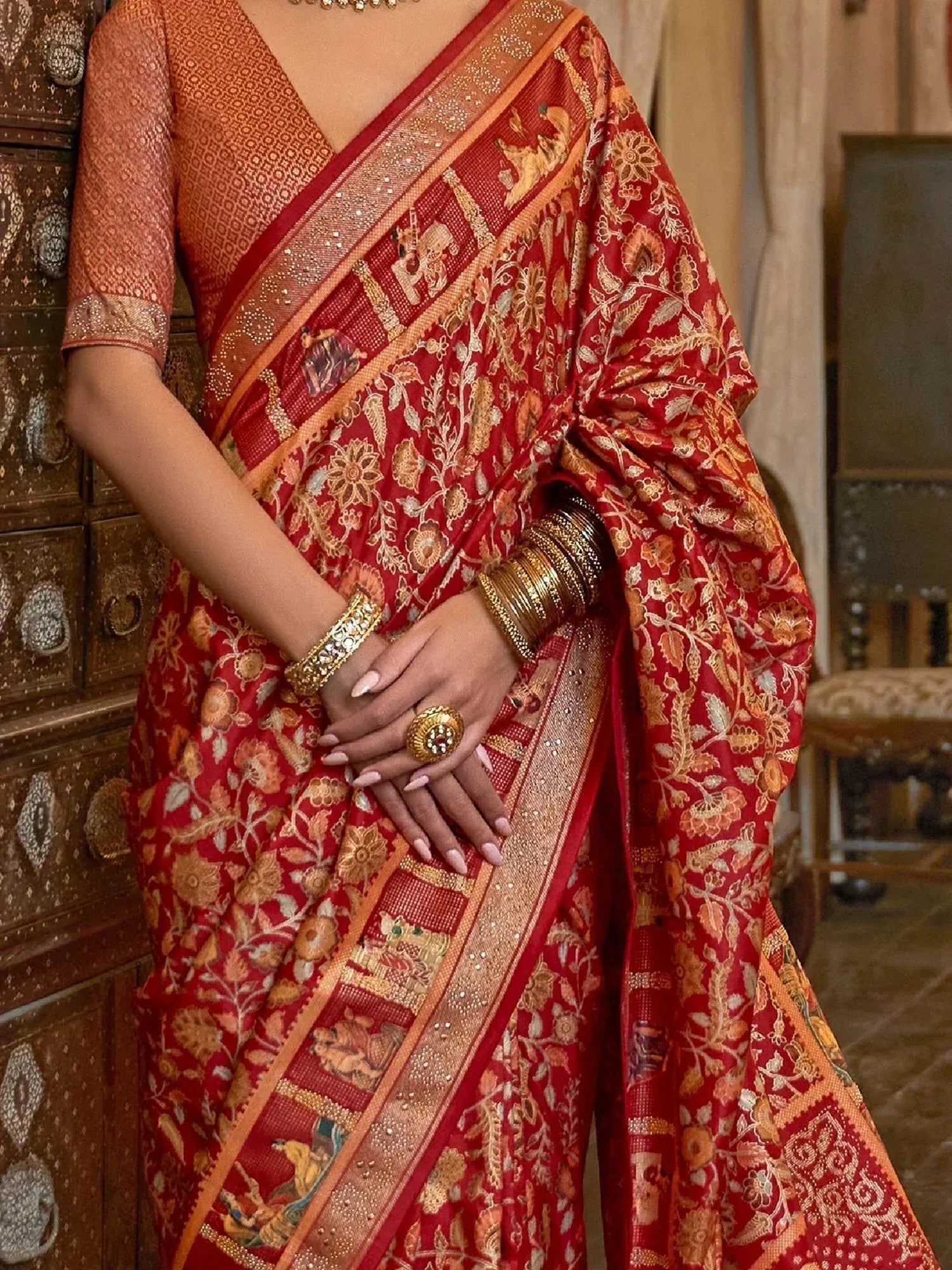 Red and gold floral saree with elephant motifs, paired with designer blouse and traditional jewelry