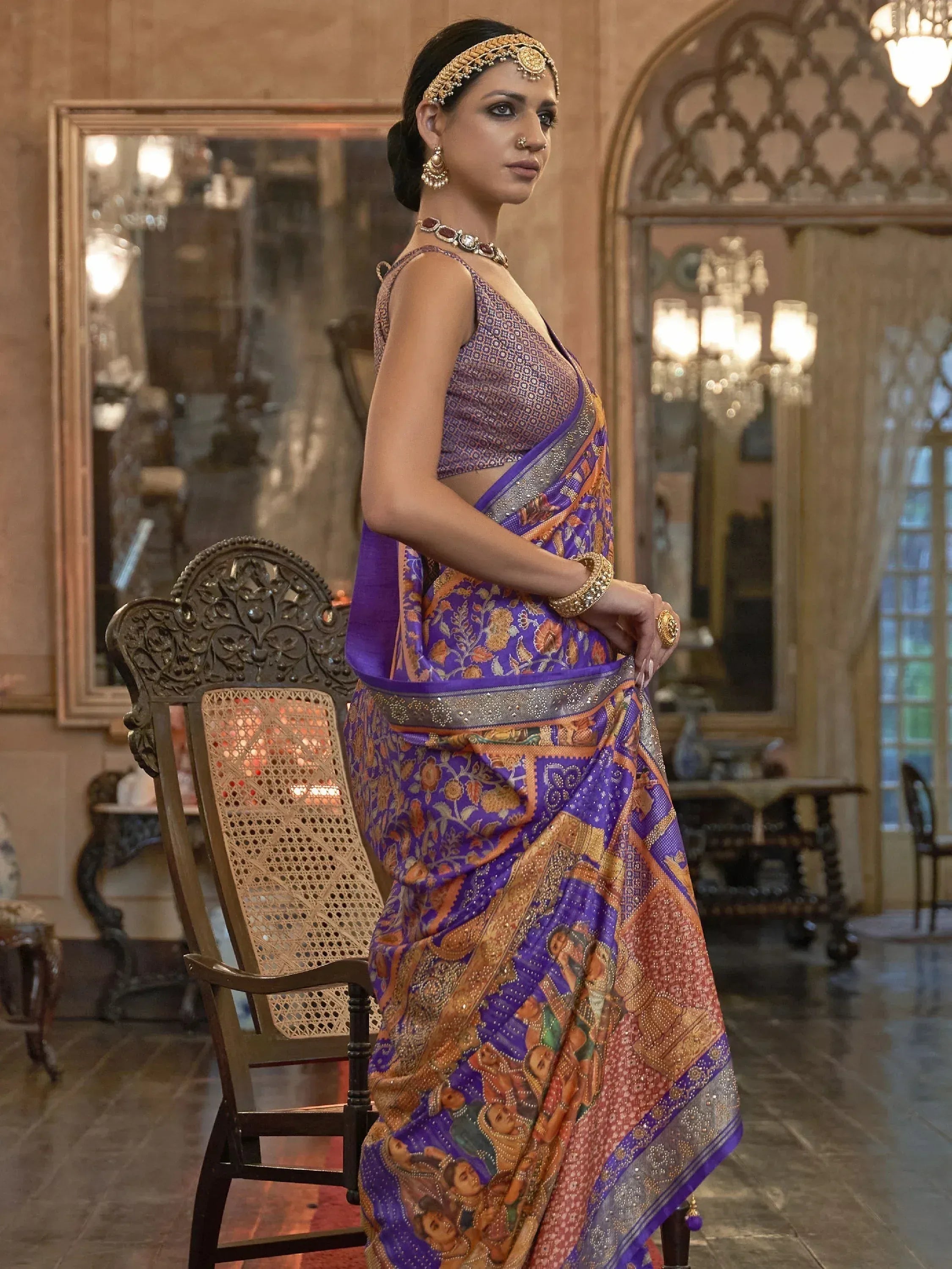 Woman in purple and gold designer saree with intricate floral and figurative print, traditional Indian ethnic wear