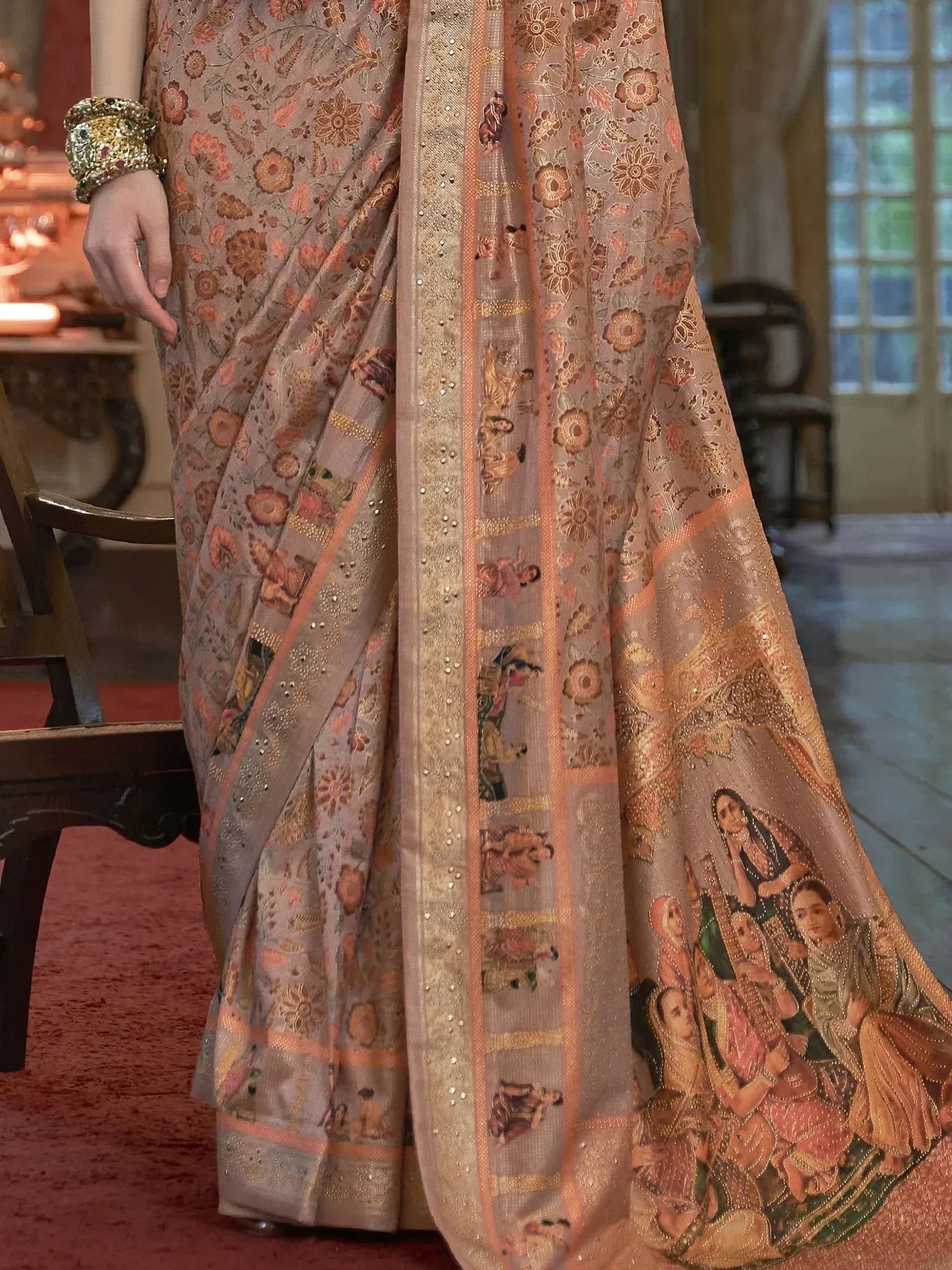 Elegant Indian saree with floral and figurative embroidery, gold border, and traditional bangles