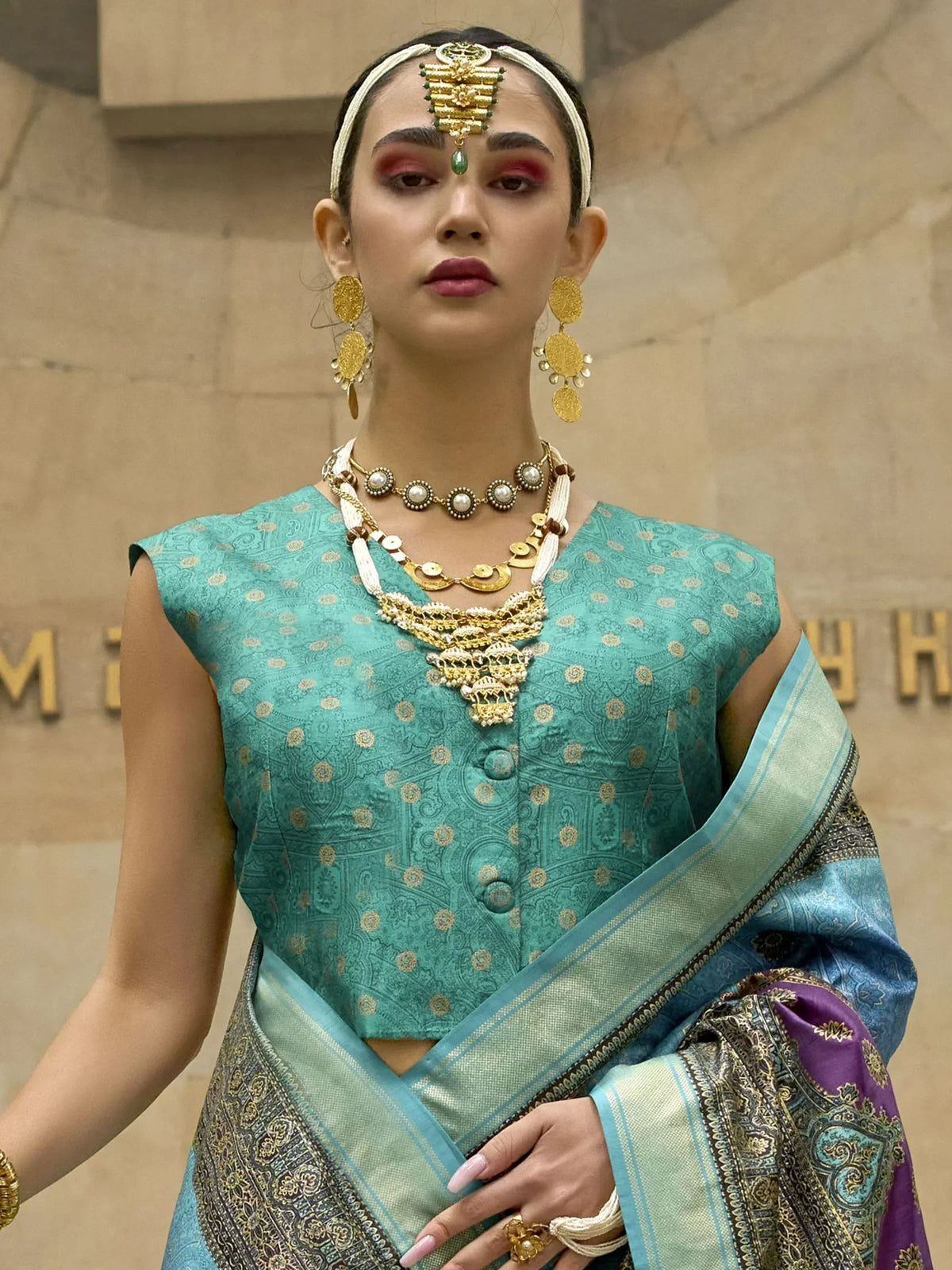 Woman in teal designer saree with gold jewelry, traditional Indian ethnic wear