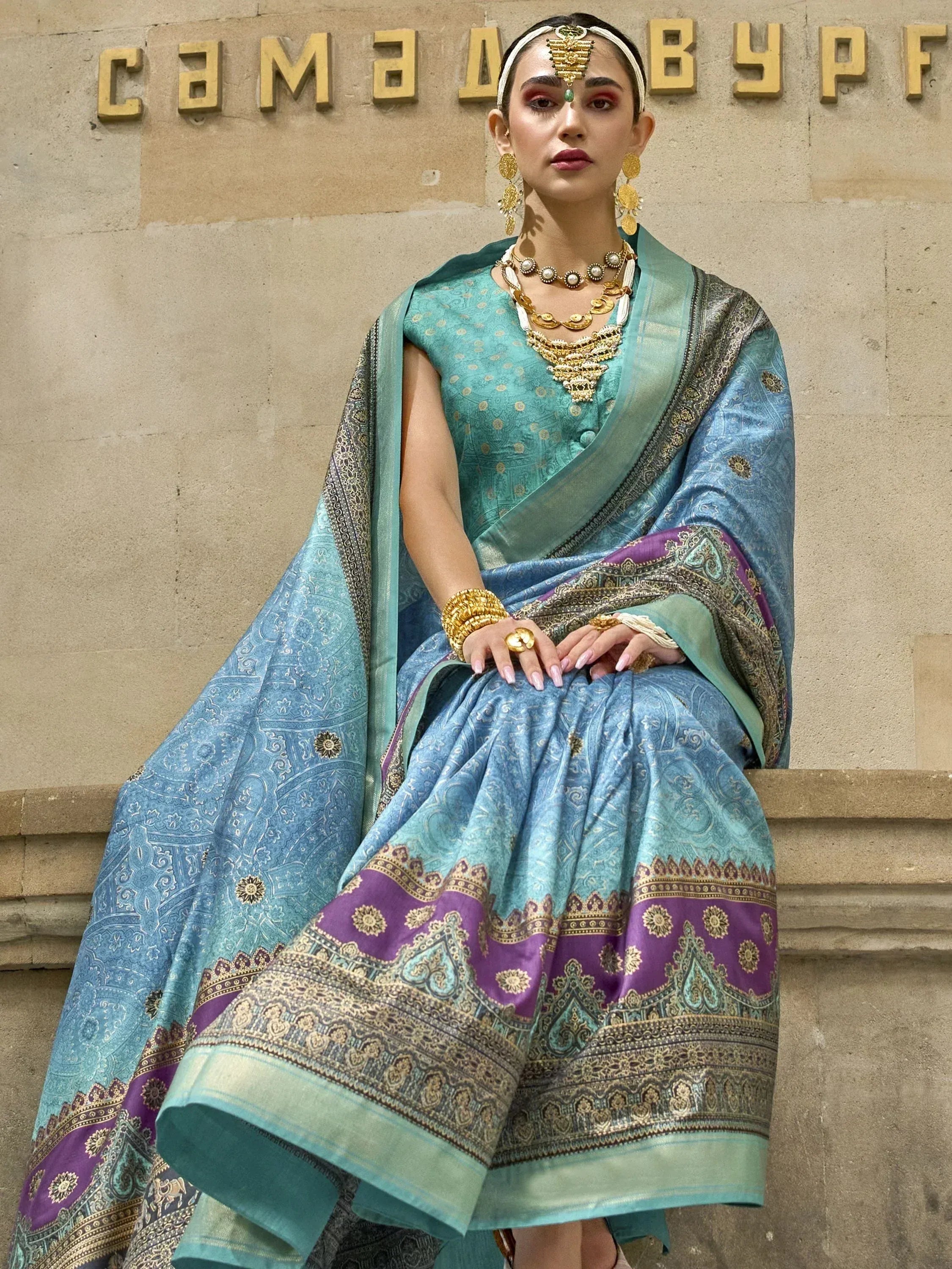 Elegant teal and purple designer lehenga choli with gold embroidery, paired with traditional jewelry for Indian ethnic wear.
