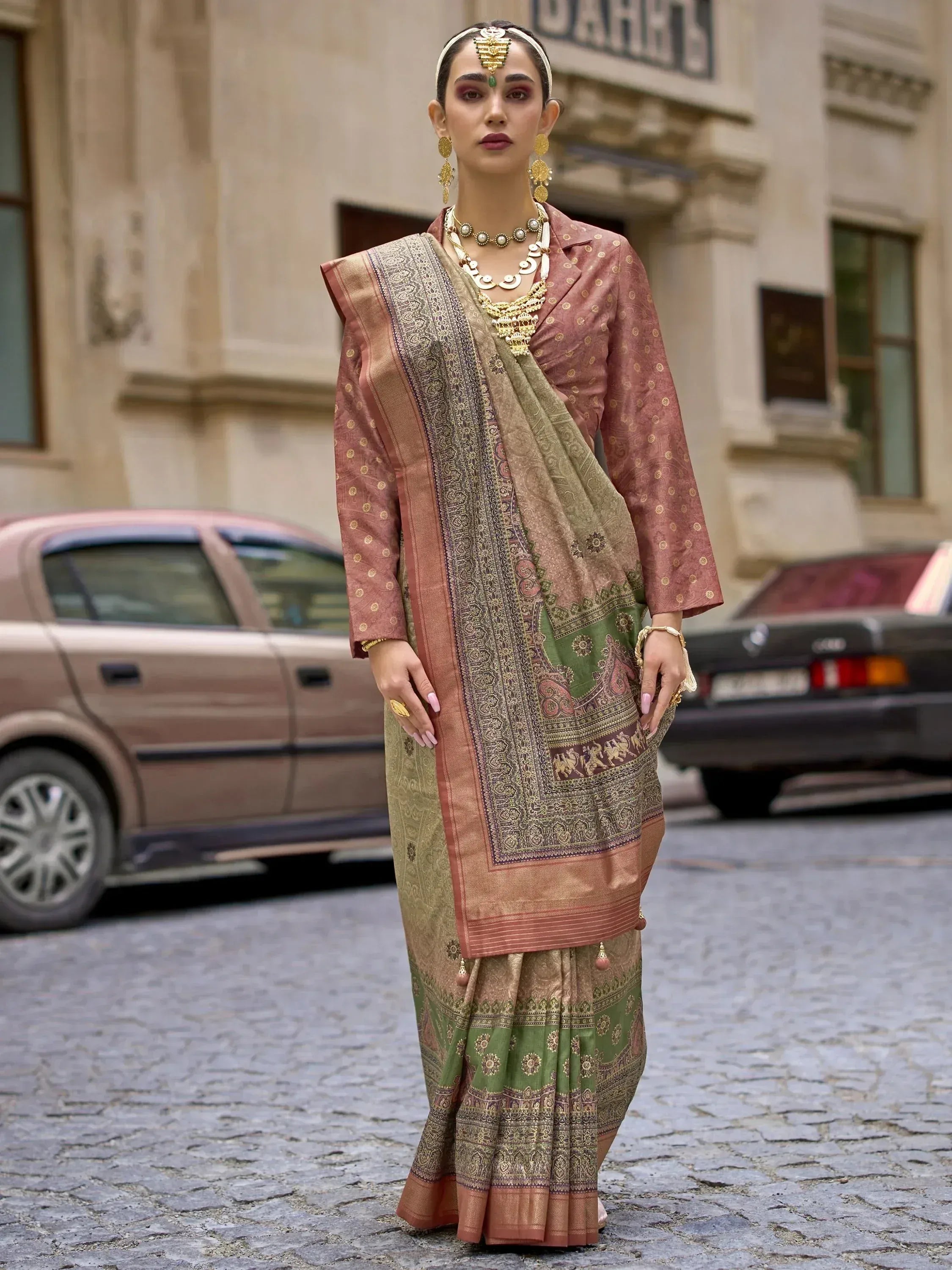 Woman in traditional Indian saree with intricate gold patterns, styled with ethnic jewelry on cobblestone street