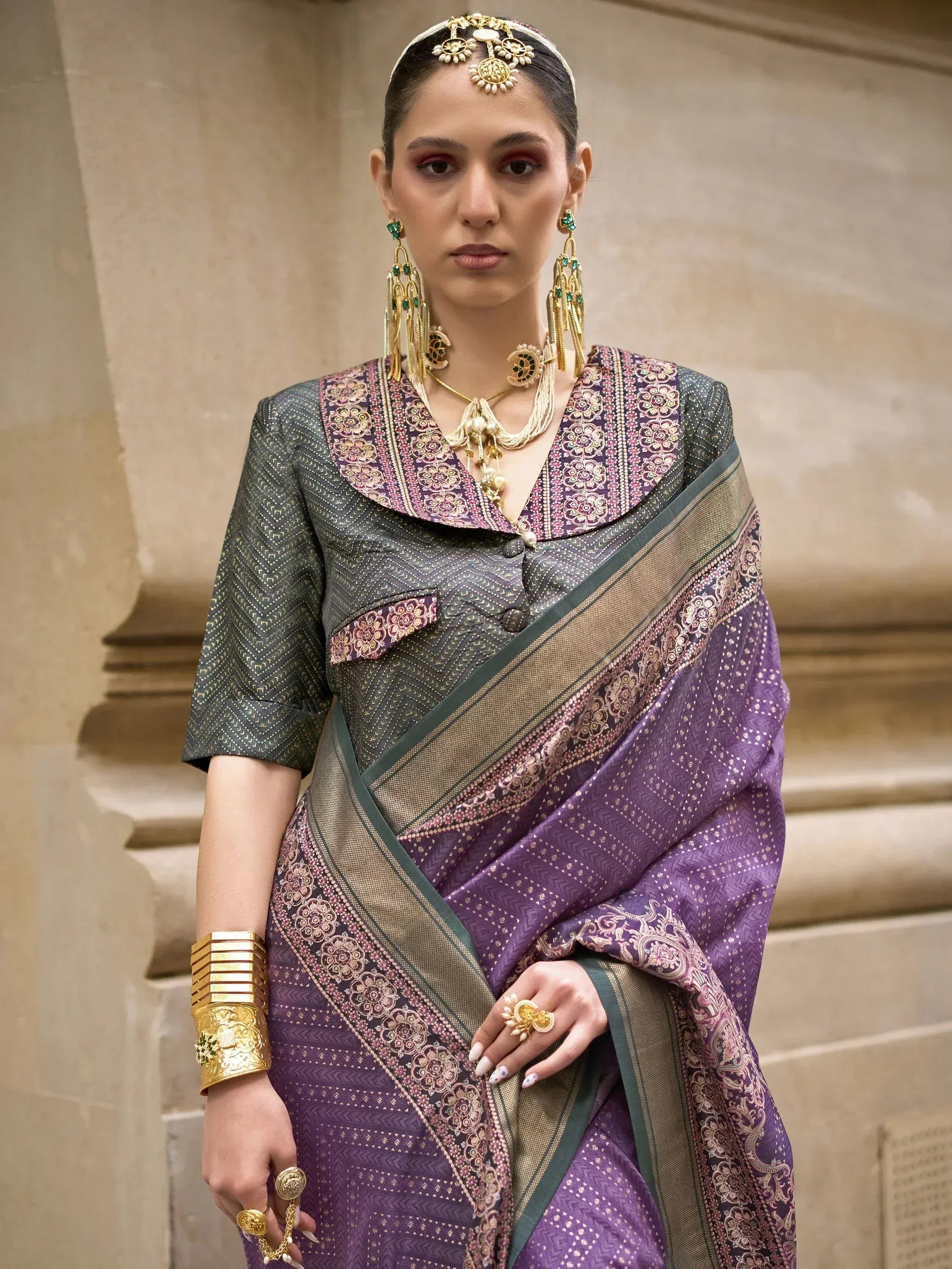 Elegant purple and green designer saree with intricate gold embroidery, paired with traditional Indian jewelry.