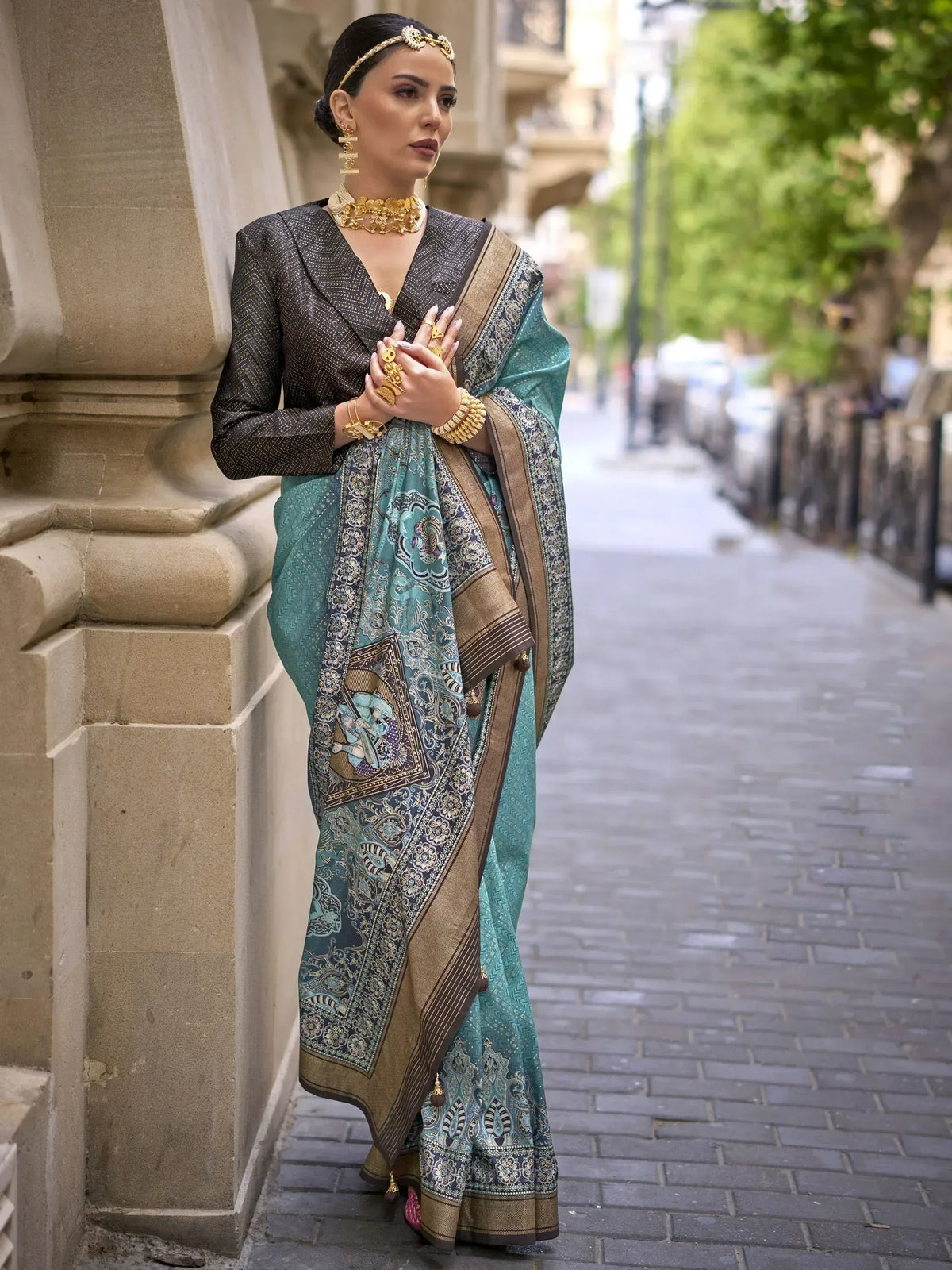 Elegant teal saree with gold border and intricate print, paired with black blouse and traditional jewelry