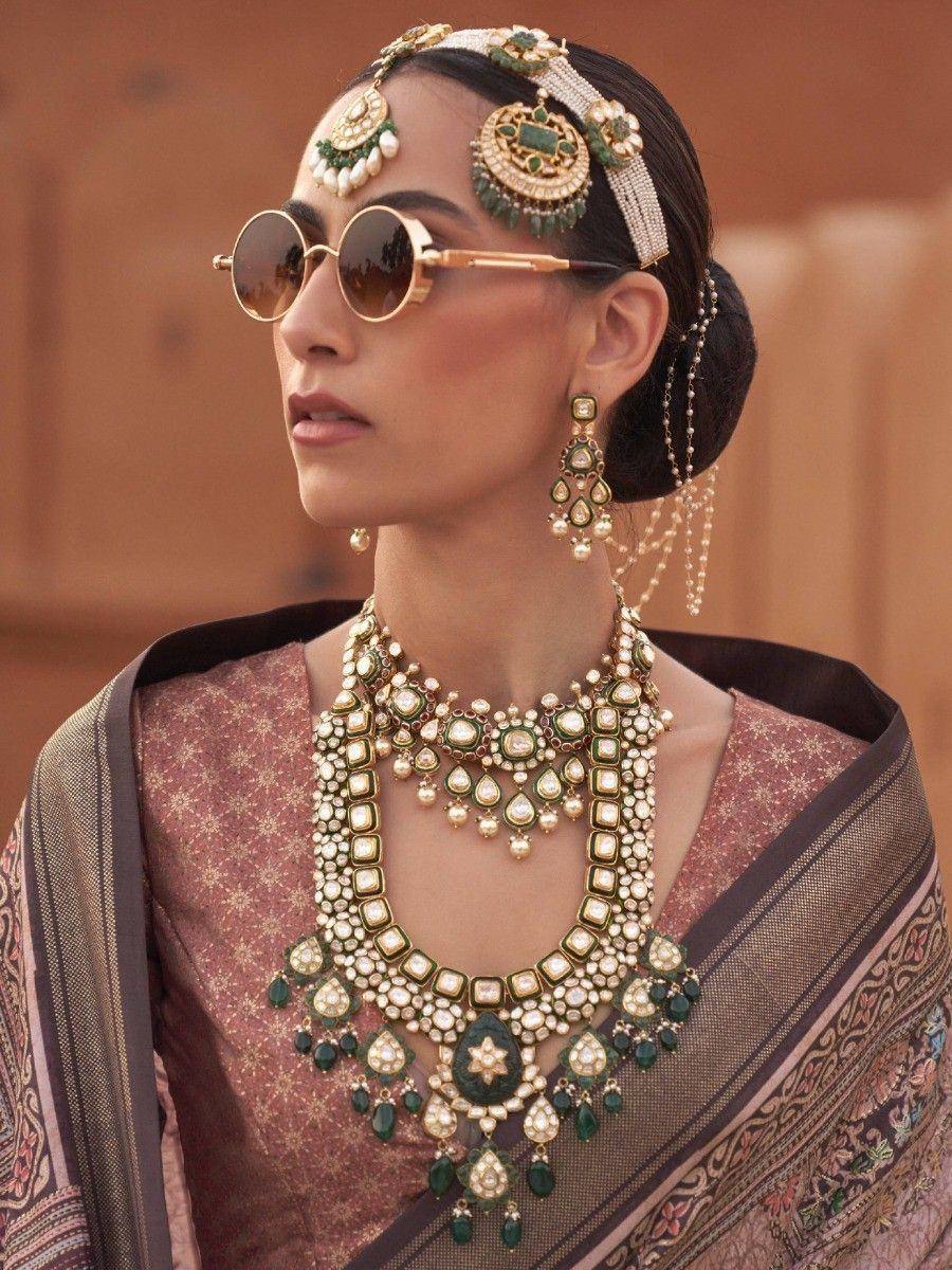 Indian ethnic wear with emerald and pearl jewelry, traditional headpiece, and sunglasses
