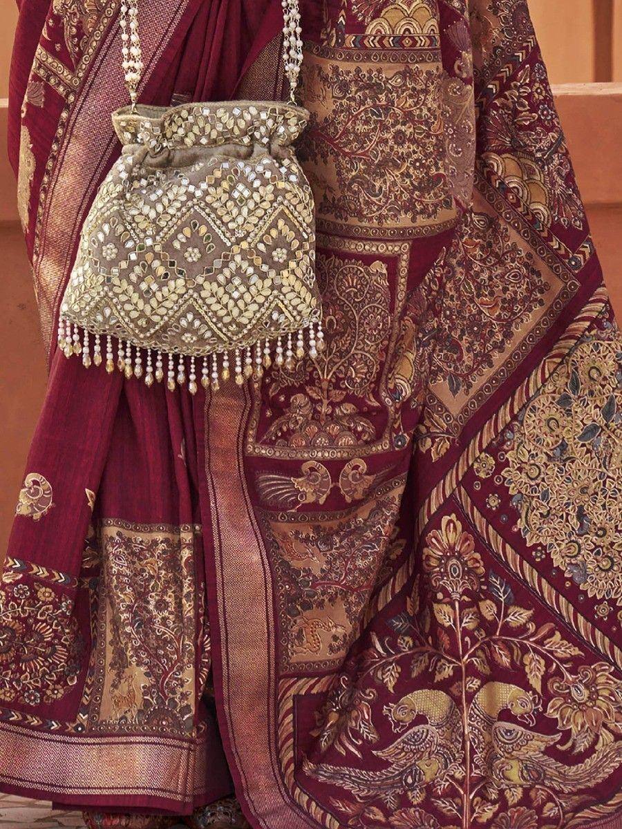 Maroon ethnic saree with gold paisley print and embellished potli bag for Indian weddings
