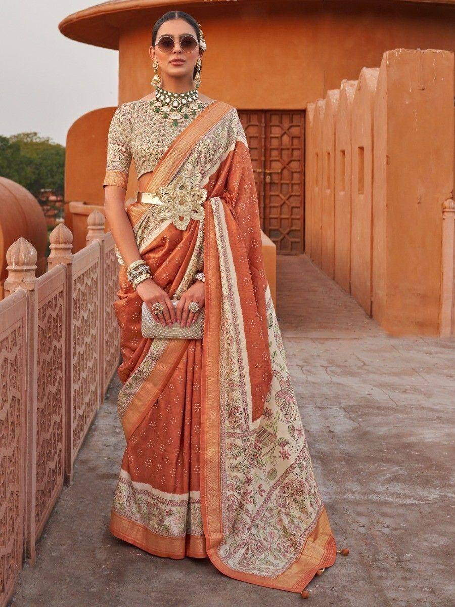 Elegant terracotta saree with floral print and gold embroidery, paired with designer blouse and statement jewelry