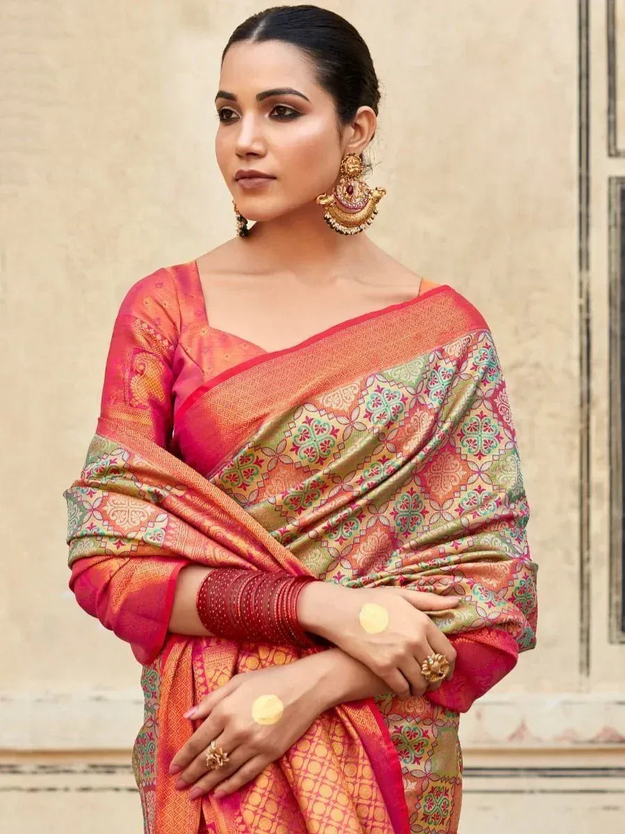 Woman in vibrant pink and gold designer saree with intricate floral patterns, traditional Indian ethnic wear