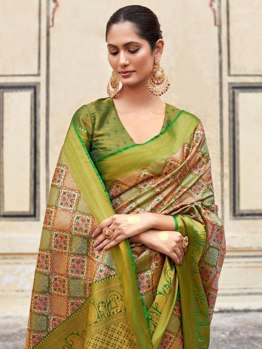 Green designer saree with intricate floral and elephant motifs, paired with gold jewelry for ethnic wear