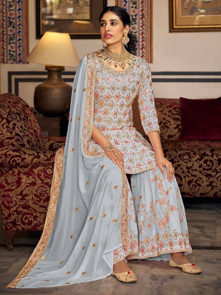Light blue embroidered sharara suit with floral motifs, gold detailing, and matching dupatta for Indian ethnic wear